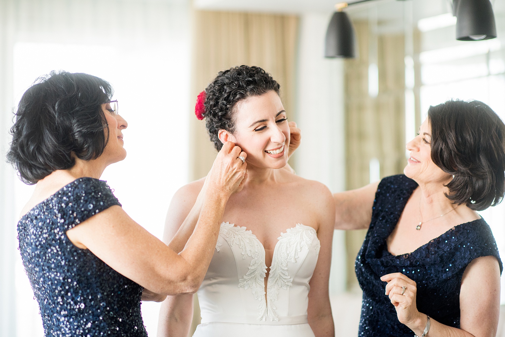 W Hoboken wedding photos by Mikkel Paige Photography. Detail picture of the bride's mother and mother-in-law helping put on her earrings. #mikkelpaige #HobokenWedding #NewJerseyPhotographer #NewYorkCityPhotographer #NYCweddingphotographer #brideandgroomphotos #redpeonies #romanticwedding #springwedding #CityWedding