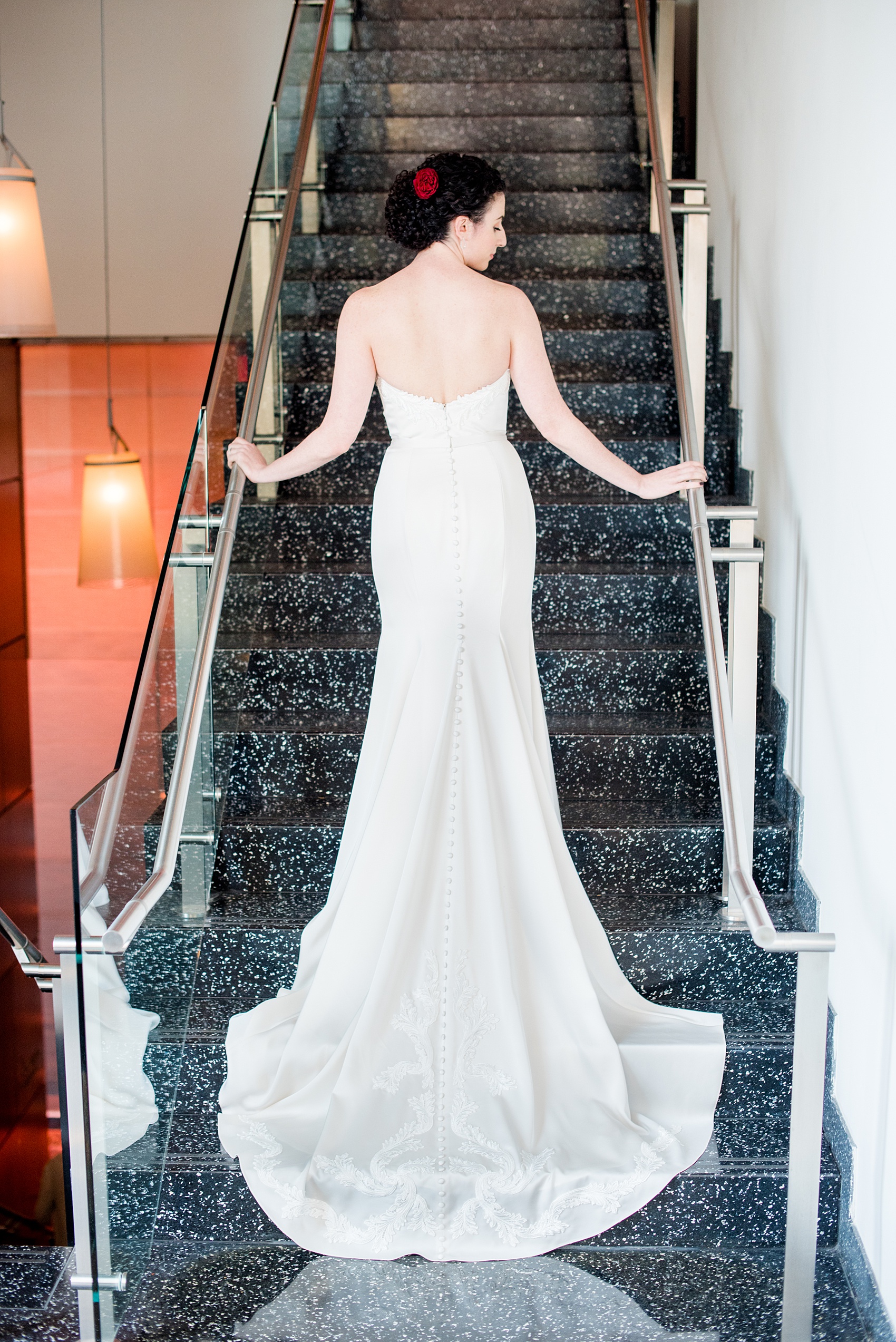 W Hoboken wedding photos by Mikkel Paige Photography. Picture of the bride in her Paloma Blanca strapless sweetheart neckline, beaded gown, with her train cascading down the stairs of the venue. #mikkelpaige #HobokenWedding #NewJerseyPhotographer #NewYorkCityPhotographer #NYCweddingphotographer #brideandgroomphotos #redpeonies #romanticwedding #springwedding #CityWedding