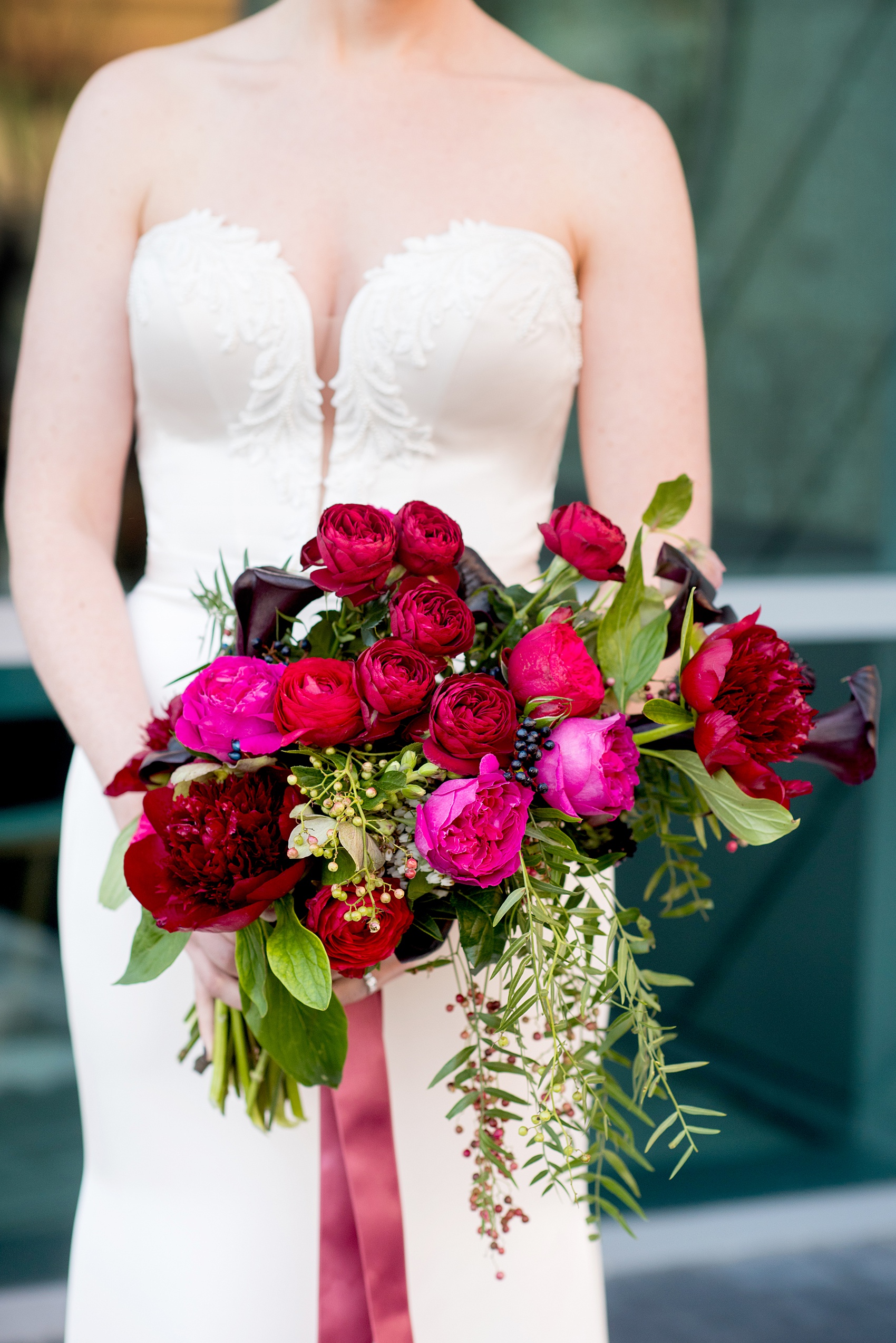 W Hoboken wedding photos by Mikkel Paige Photography at this NJ venue. Pictures in this well known New Jersey city with a view of the NYC skyline. This detail image is of the semi-cascading bouquet includes red, fuchsia and burgundy peonies, calla lilies, Japanese roses, helebores dahlias and ranunculus by Sachi Rose Design. #mikkelpaige #HobokenWedding #NewJerseyPhotographer #NewYorkCityPhotographer #NYCweddingphotographer #brideandgroomphotos #redpeonies #romanticwedding #springwedding #CityWedding