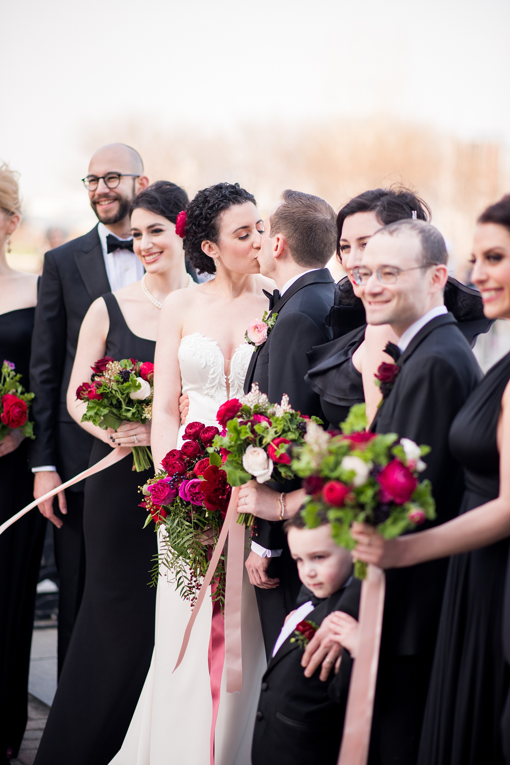 W Hoboken wedding photos at this New Jersey hotel overlooking the NYC skyline. Candid photos by Mikkel Paige Photography of the bridal party in black gowns carrying romantic bouquets in red and pink and groomsmen in black tuxedos. #mikkelpaige #HobokenWedding #NewJerseyPhotographer #NewYorkCityPhotographer #NYCweddingphotographer #brideandgroomphotos #redpeonies #romanticwedding #springwedding #CityWedding
