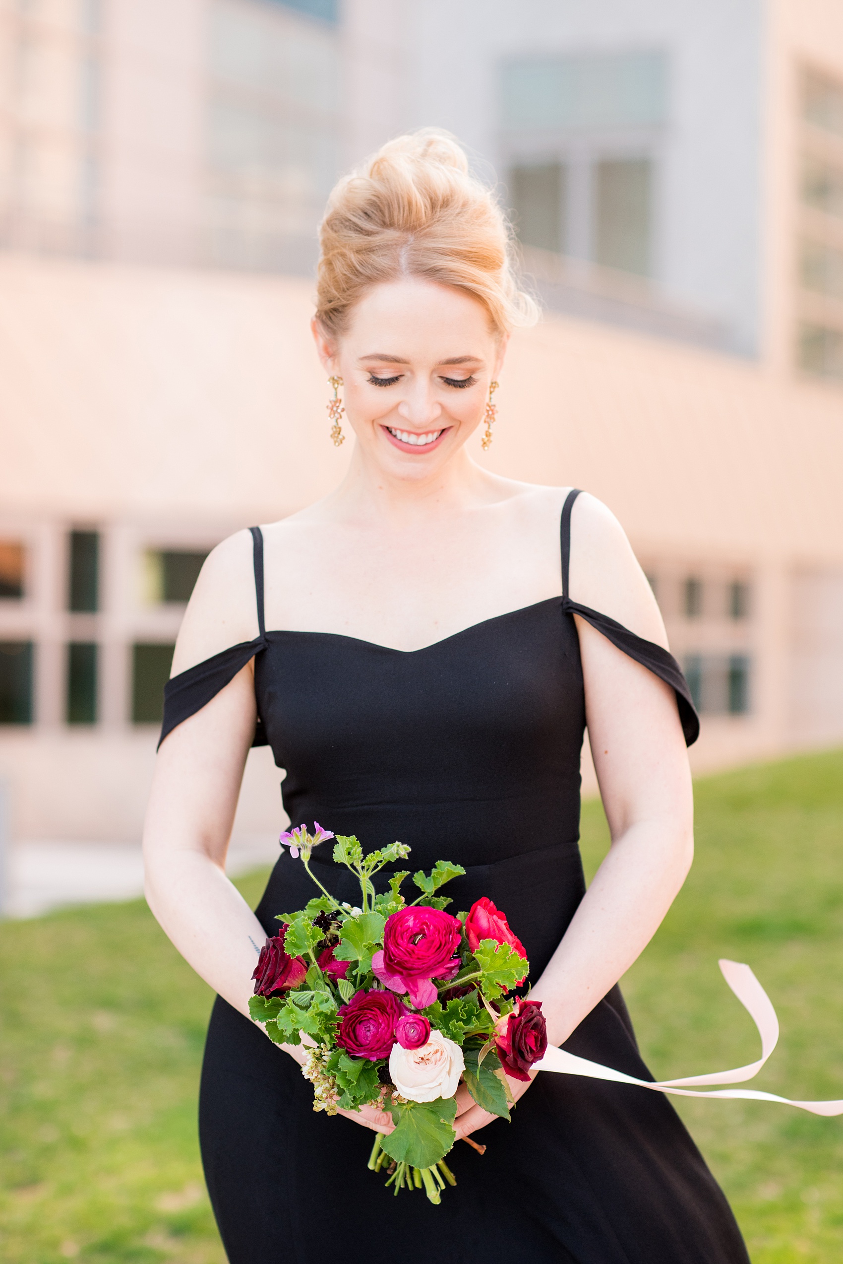 W Hoboken wedding photos by Mikkel Paige Photography at this New Jersey hotel overlooking the NYC skyline. Picture of the bridesmaid with a french twist up do, black off-the-shoulder gown and carrying a romantic bouquet in red and pink with long ribbons. #mikkelpaige #HobokenWedding #NewJerseyPhotographer #NewYorkCityPhotographer #NYCweddingphotographer #brideandgroomphotos #redpeonies #romanticwedding #springwedding #CityWedding