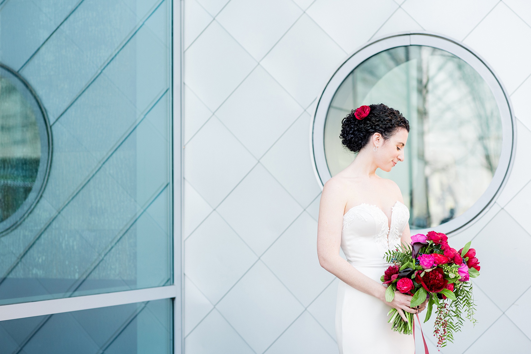 W Hoboken wedding photos by Mikkel Paige Photography. Iconic picture of the bride in her strapless Paloma Blanca gown in this well known New Jersey city with a view of the NYC skyline across the Hudson River. Beautiful red, burgundy, fuchsia and pink peony and calla lily bouquet by Sachi Rose Designs. #mikkelpaige #HobokenWedding #NewJerseyPhotographer #NewYorkCityPhotographer #NYCweddingphotographer #brideandgroomphotos #redpeonies #romanticwedding #springwedding #CityWedding