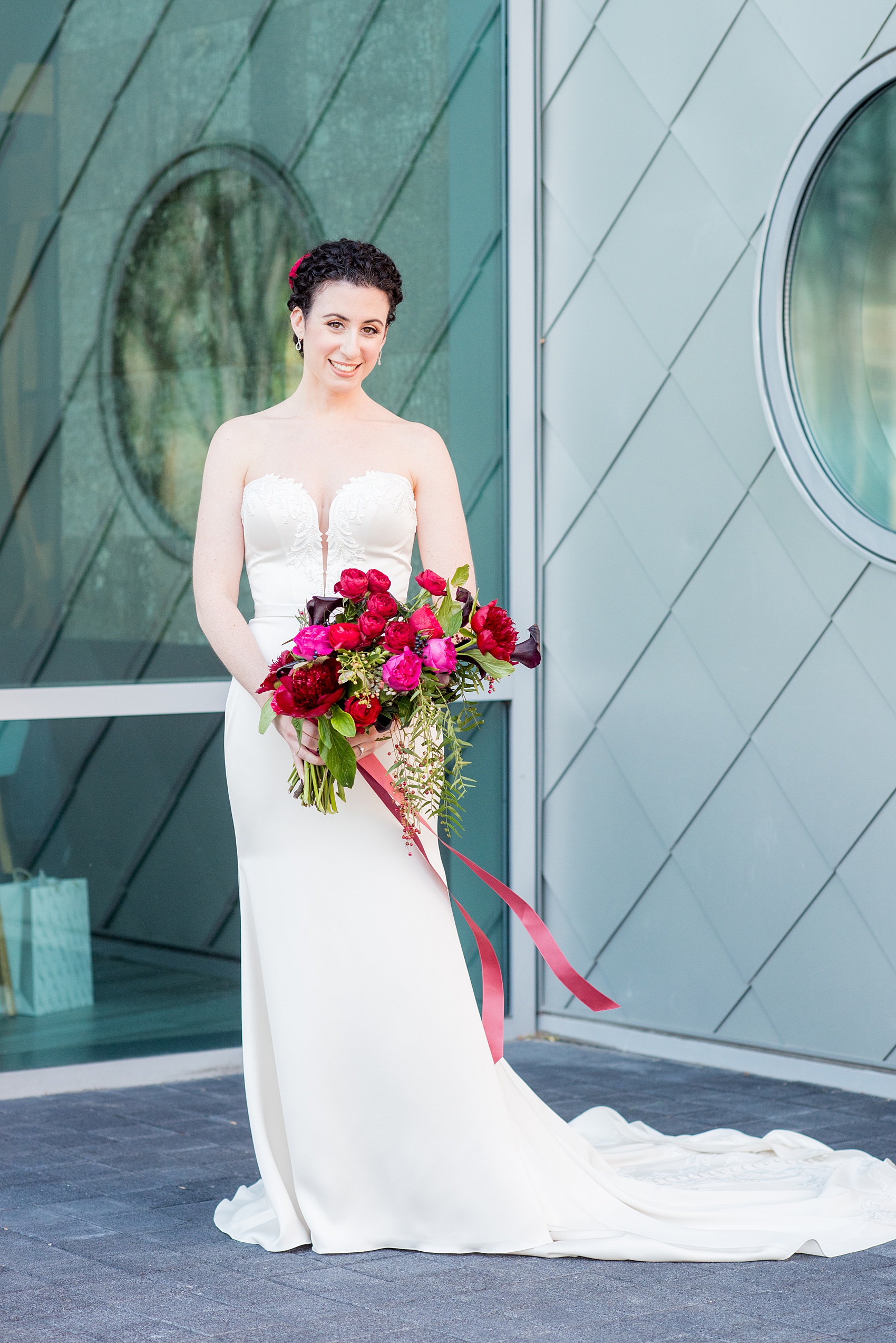 W Hoboken wedding photos by Mikkel Paige Photography. Picture of the bride in her strapless Paloma Blanca gown in this well known New Jersey city with a view of the NYC skyline across the Hudson River. #mikkelpaige #HobokenWedding #NewJerseyPhotographer #NewYorkCityPhotographer #NYCweddingphotographer #brideandgroomphotos #redpeonies #romanticwedding #springwedding #CityWedding