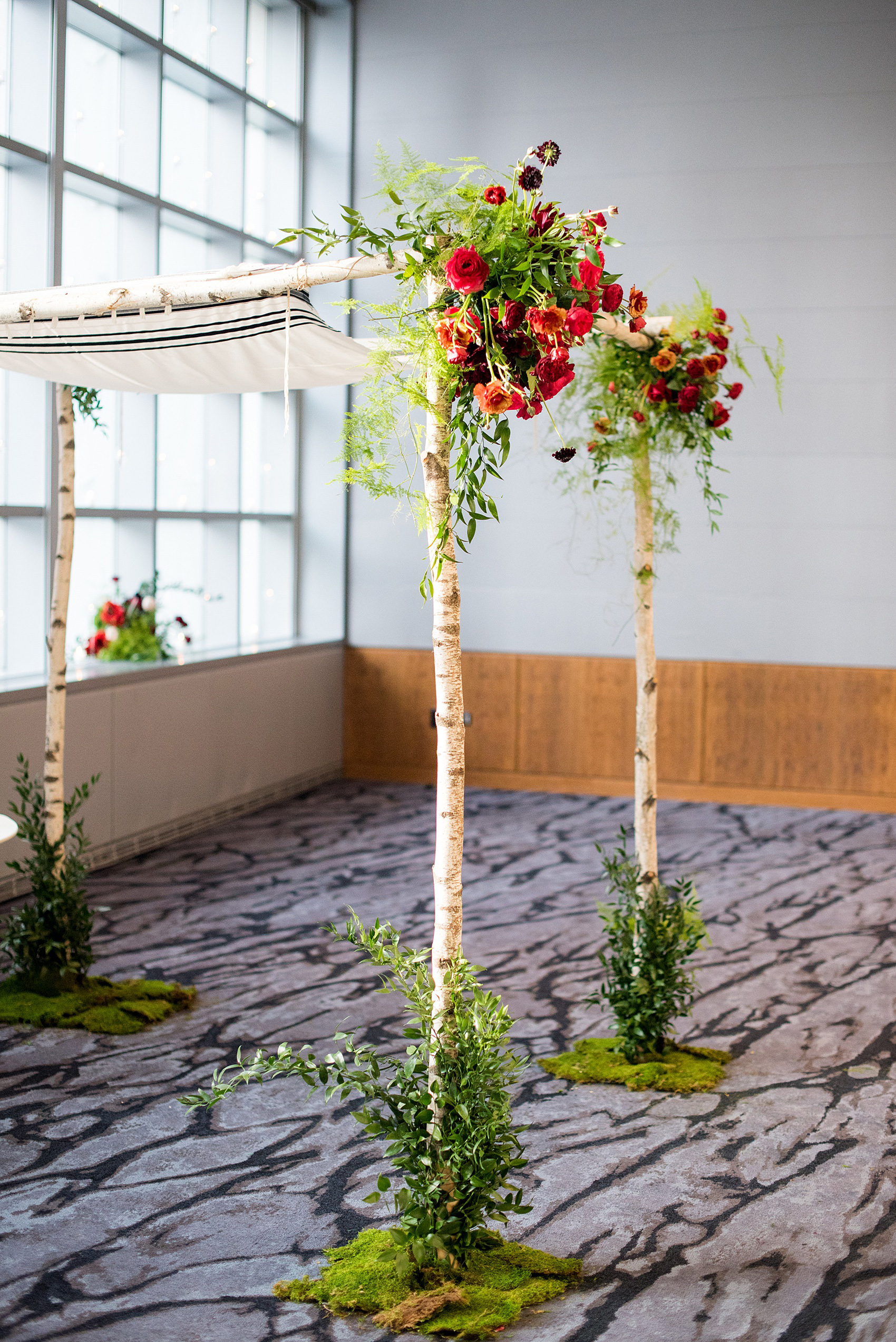 W Hoboken wedding photos at this New Jersey venue overlooking the NYC skyline by Mikkel Paige Photography. Picture of the indoor ceremony birch branch chuppah. Sachi Rose Design decorated it with red, pink, fuchsia and burgundy flowers. #mikkelpaige #HobokenWedding #NewJerseyPhotographer #NewYorkCityPhotographer #NYCweddingphotographer #brideandgroomphotos #redpeonies #romanticwedding #springwedding #CityWedding #JewishWedding #Chuppah