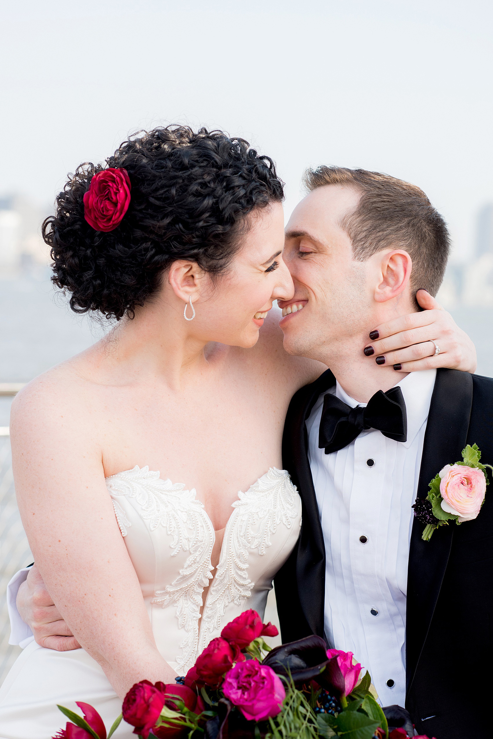 W Hoboken Wedding Photos by Mikkel Paige Photography. Spring wedding overlooking the NYC skyline, with a sexy black, deep red, burgundy and fuchsia color palette. Picture of the bride and groom laughing and kissing. #HobokenWedding #mikkelpaige #springwedding #romanticwedding #NewJerseyWeddingPhotos
