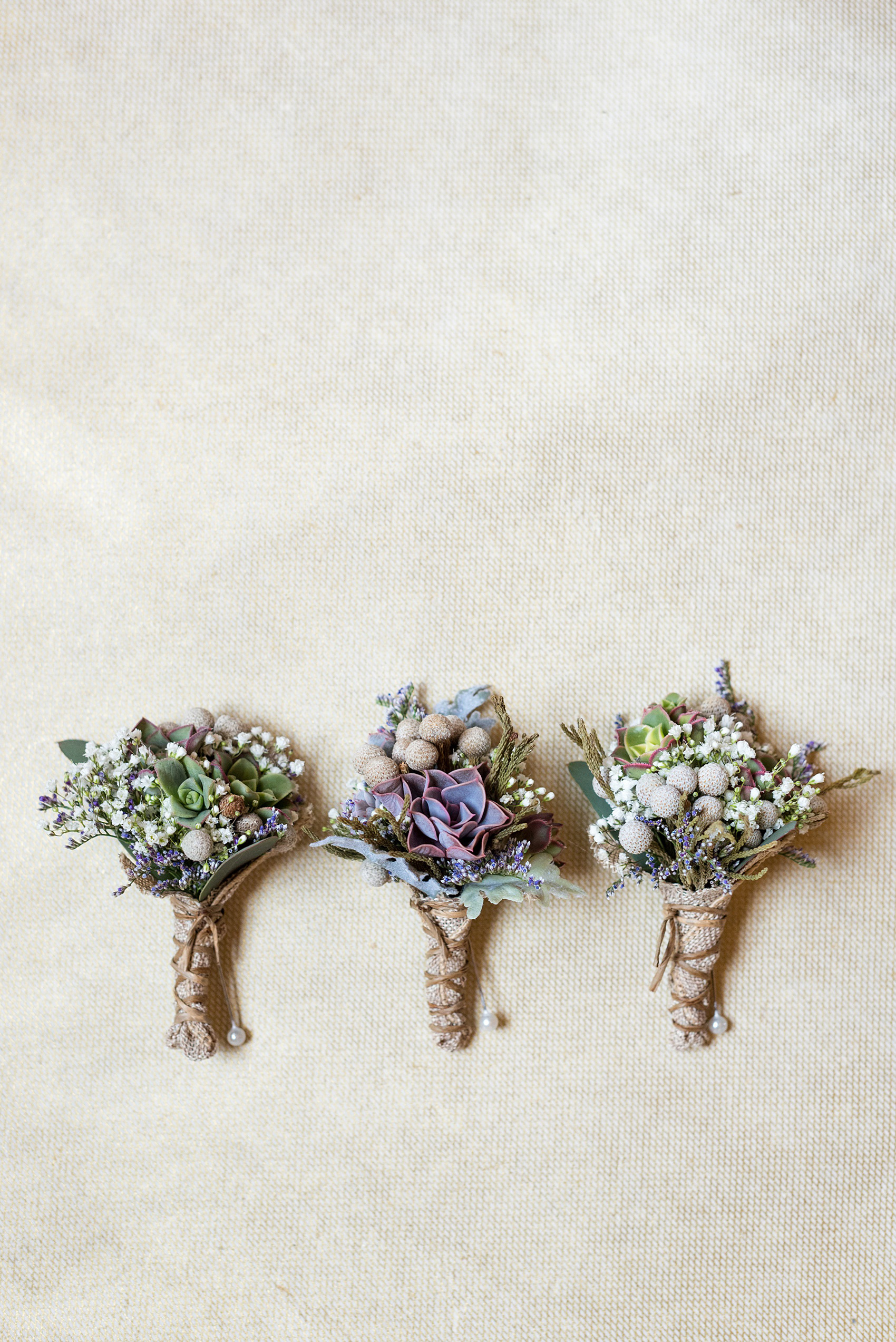 Crystal Springs Resort wedding photos in New Jersey, with photographer Mikkel Paige Photography. The couple’s spring wedding had an outdoor ceremony with photos at this rustic, woodsy venue showing their blue and pink palette decor from getting ready to their reception. This detail picture shows the groom and groomsmen's succulent and silver brunia boutonnieres wrapped with raffia and burlap. Click through to see their complete wedding recap! #NewJerseywedding #MikkelPaige #NJweddingphotographer #NJphotographer #succulents #succulentboutonniere #groomsboutonniere #boutonniere