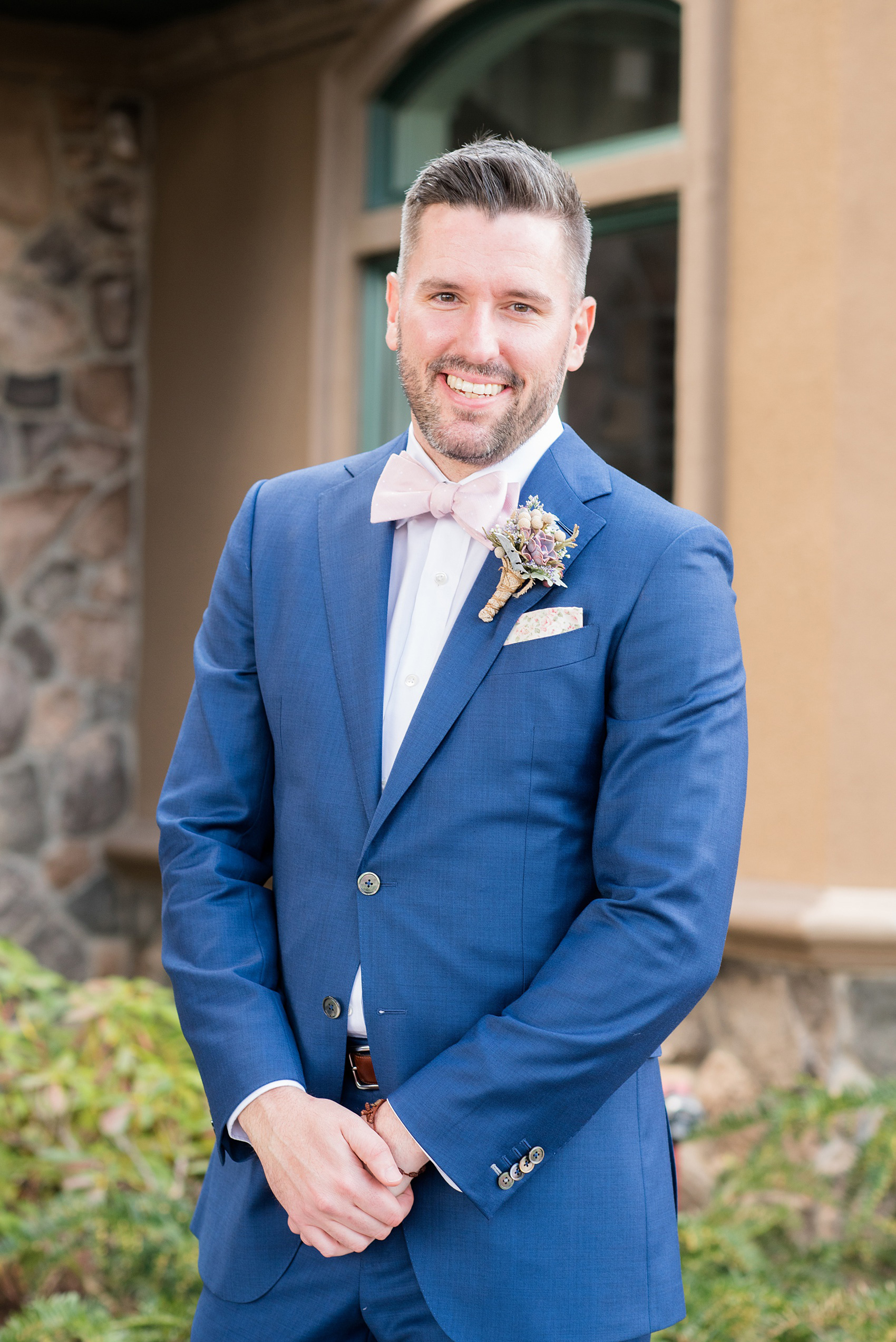 Crystal Springs Resort wedding photos in New Jersey, with photographer Mikkel Paige Photography. The couple’s spring wedding had an outdoor ceremony with photos at this rustic, woodsy venue showing their blue and pink palette decor from getting ready to their reception. This picture shows the groom in his custom navy blue suit with a succulent boutonniere. Click through to see their complete wedding recap! #NewJerseywedding #MikkelPaige #NJweddingphotographer #NJphotographer #customsuit #groom #weddingdetails #pinkbowtie 