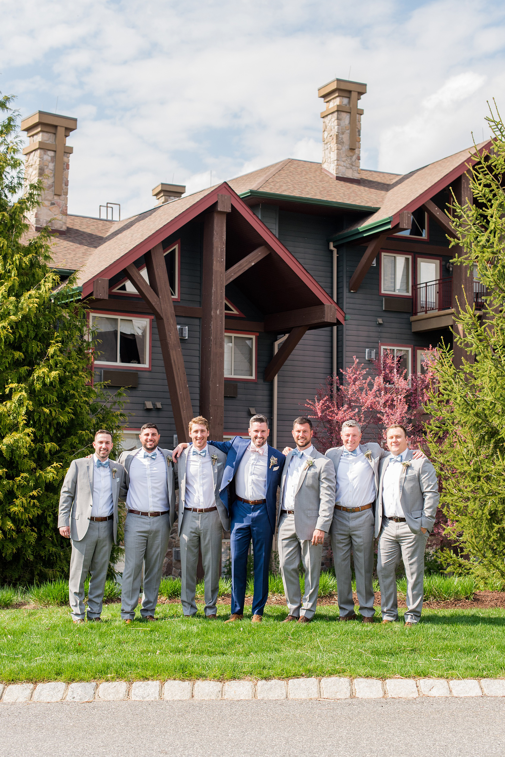 Crystal Springs Resort wedding photos in New Jersey, with photographer Mikkel Paige Photography. The couple’s spring wedding had an outdoor ceremony with photos at this rustic, woodsy venue showing their blue and pink palette decor from getting ready to their reception. This picture shows the groomsmen in their grey suits and blue bow ties with the groom in a custom navy suit and pink bow tie. Click through to see their complete wedding recap! #NewJerseywedding #MikkelPaige #NJweddingphotographer #NJphotographer #brideandgroom #springwedding #pinkandblue #weddingparty #groomsmen #bowties