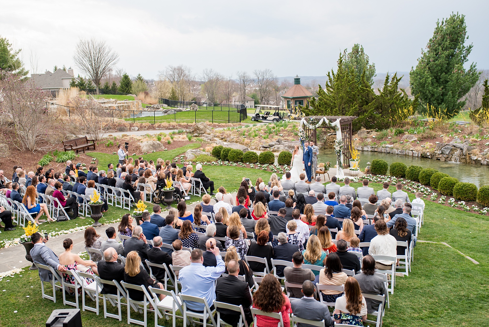 Crystal Springs Resort wedding photos in New Jersey, with photographer Mikkel Paige Photography. The couple’s spring wedding had an outdoor ceremony with photos at this rustic, woodsy venue showing their blue and pink palette decor from getting ready to their reception. This photo shows a semi-aerial view of the ceremony. Click through to see their complete wedding recap! #NewJerseywedding #MikkelPaige #NJweddingphotographer #NJphotographer #springwedding #pinkandblue #outdoorceremony #herecomesthebride