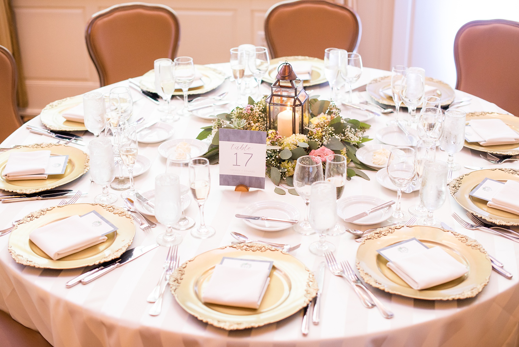 Crystal Springs Resort wedding photos in New Jersey, with photographer Mikkel Paige Photography. The couple’s spring wedding had an outdoor ceremony with photos at this rustic, woodsy venue showing their blue and pink palette decor from getting ready to their reception. This detail picture shows the reception tables with gold chargers and lanterns surrounded by flowers. Click through to see their complete wedding recap! #NewJerseywedding #MikkelPaige #NJweddingphotographer #NJphotographer #springwedding #pinkandblue #receptiontable