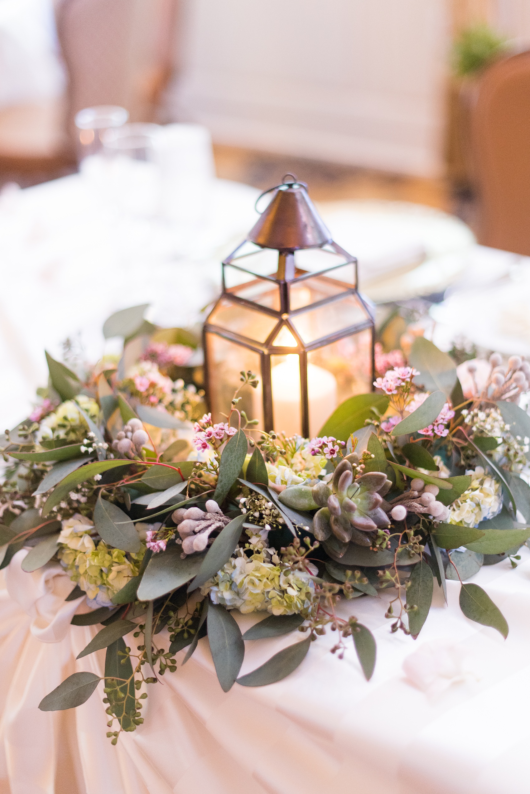 Crystal Springs Resort wedding photos in New Jersey, with photographer Mikkel Paige Photography. The couple’s spring wedding had an outdoor ceremony with photos at this rustic, woodsy venue showing their blue and pink palette decor from getting ready to their reception. This detail picture shows the reception centerpieces: lanterns surrounded by flowers, including eucalyptus and wax flowers. Click through to see their complete wedding recap! #NewJerseywedding #MikkelPaige #NJweddingphotographer #NJphotographer #springwedding #pinkandblue #receptiontable #floralcenterpieces #eucalyptuscenterpieces #lanterncenterpieces