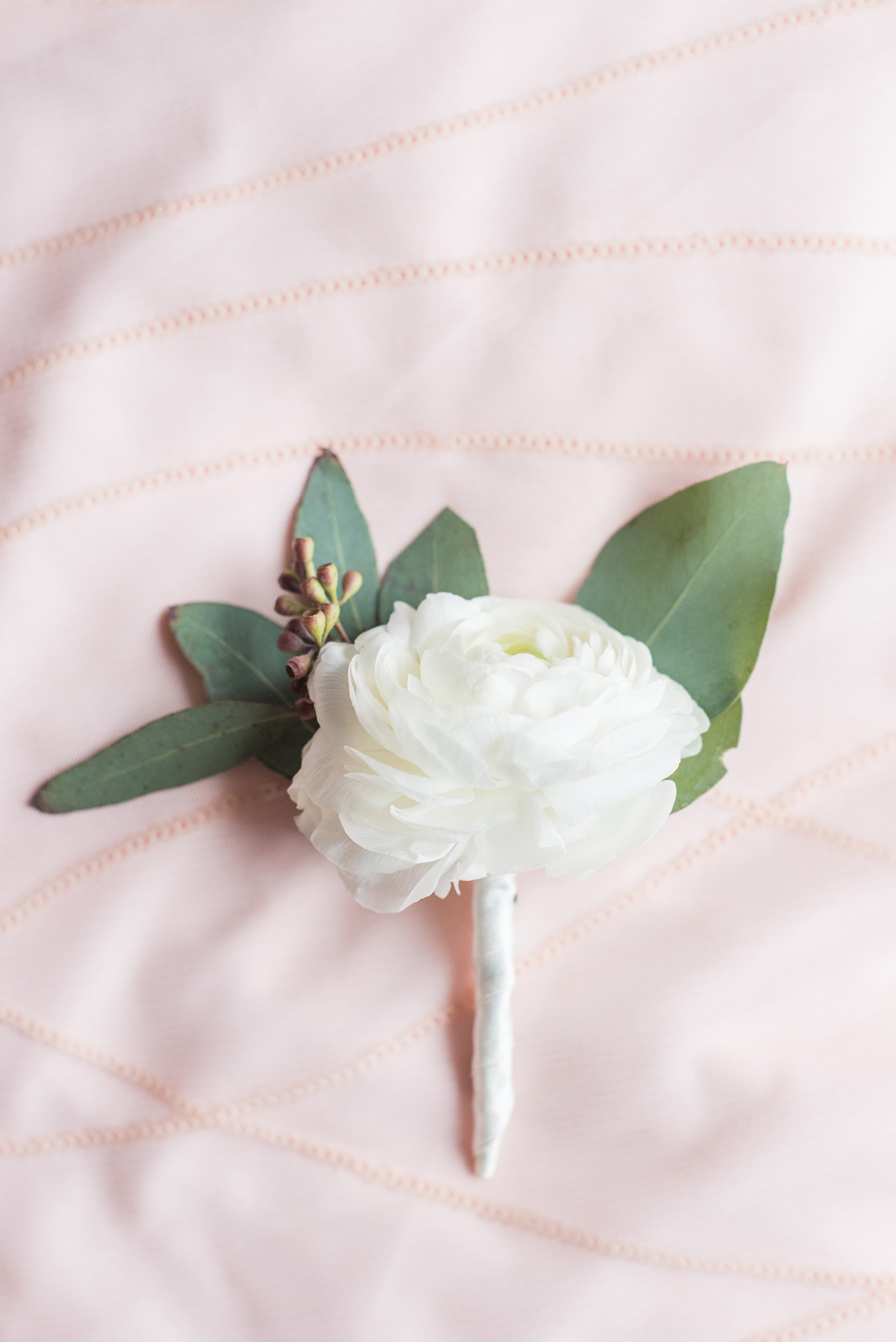 The Rickhouse wedding photos by Mikkel Paige photography in Durham, North Carolina. This urban venue has all the charm of the south for this bride and groom's spring wedding! This detail picture shows the groom's white ranunculus boutonniere with eucalyptus filler. Click through to see the complete post! #mikkelpaige #northcarolina #southernwedding #TheRickhouseDurham #rosegoldandpink #boutonniere #ranunculus