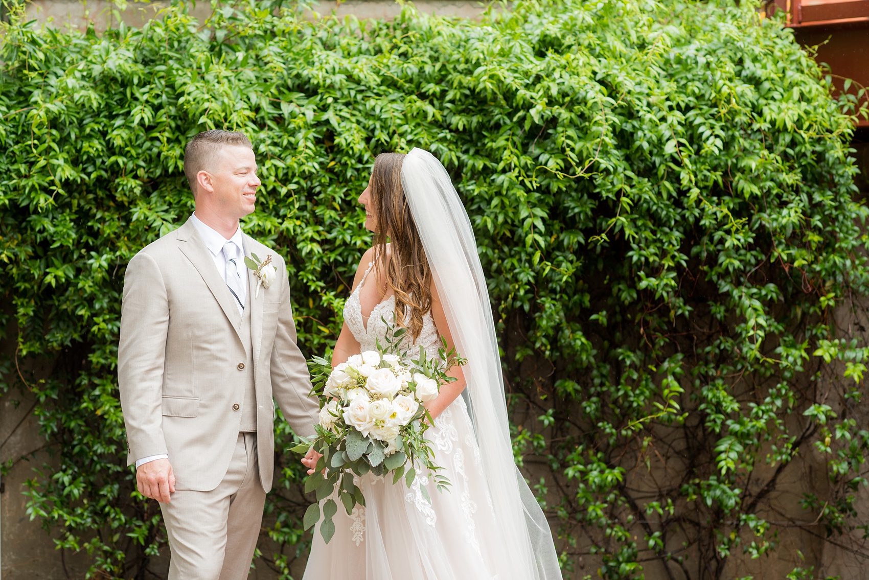 The Rickhouse wedding photos by Mikkel Paige photography in Durham, North Carolina. This urban venue has all the charm of the south for this bride and groom's spring wedding! This picture shows the bride and groom at American Tobacco Campus against a gorgeous wall of green ivy. Click to see more from their day! #mikkelpaige #northcarolina #southernwedding #TheRickhouseDurham #rosegoldandpink #brideandgroom