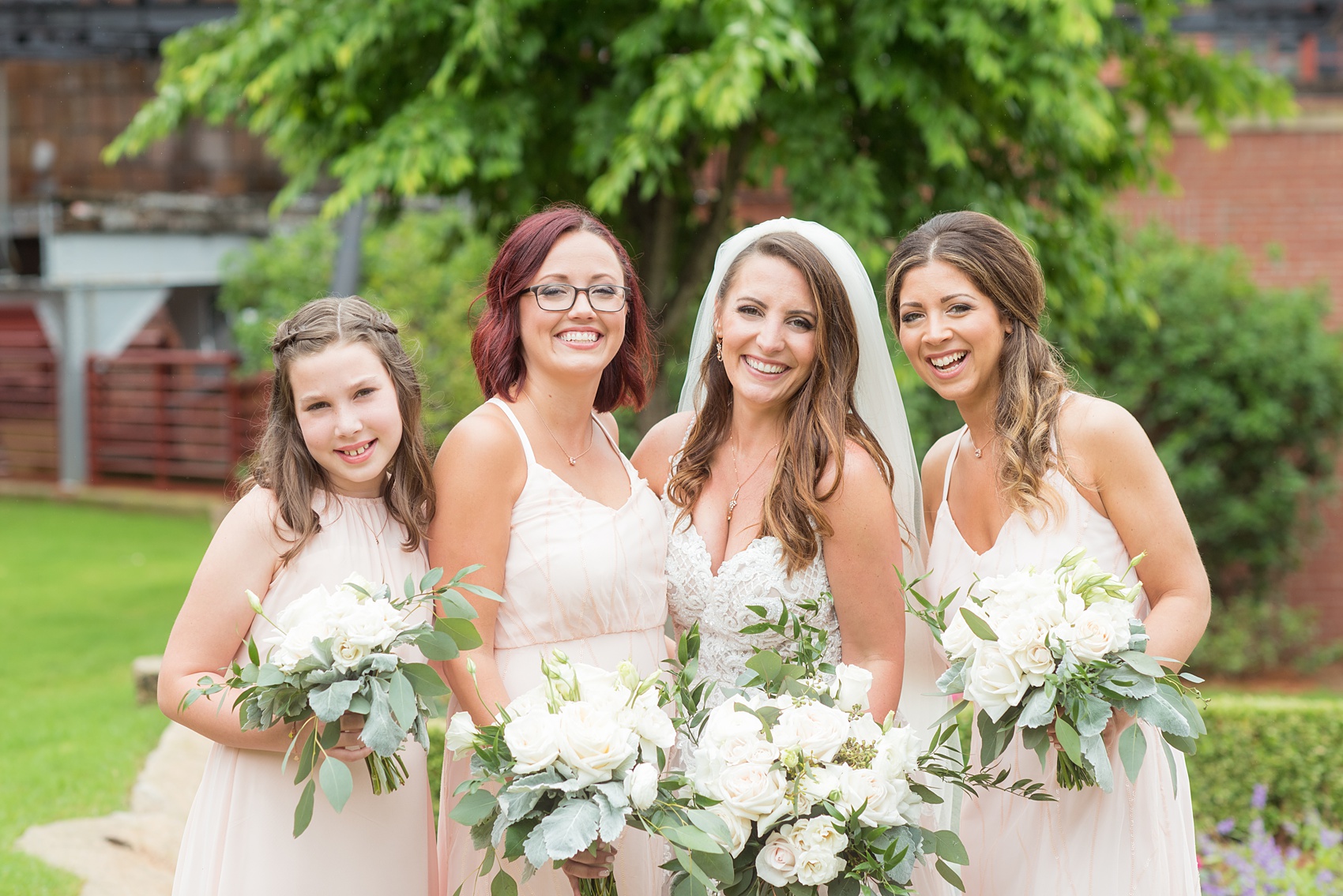 The Rickhouse wedding photos by Mikkel Paige photography in Durham, North Carolina. This urban venue has all the charm of the south for this bride and groom's spring wedding! This picture shows the bridal party posing for a photo with pink gowns and white bouquets at American Tobacco Campus. Click to see more from their day! #mikkelpaige #northcarolina #southernwedding #TheRickhouseDurham #rosegoldandpink #rainywedding #weddingintherain #bridalparty #pinkbridesmaids 