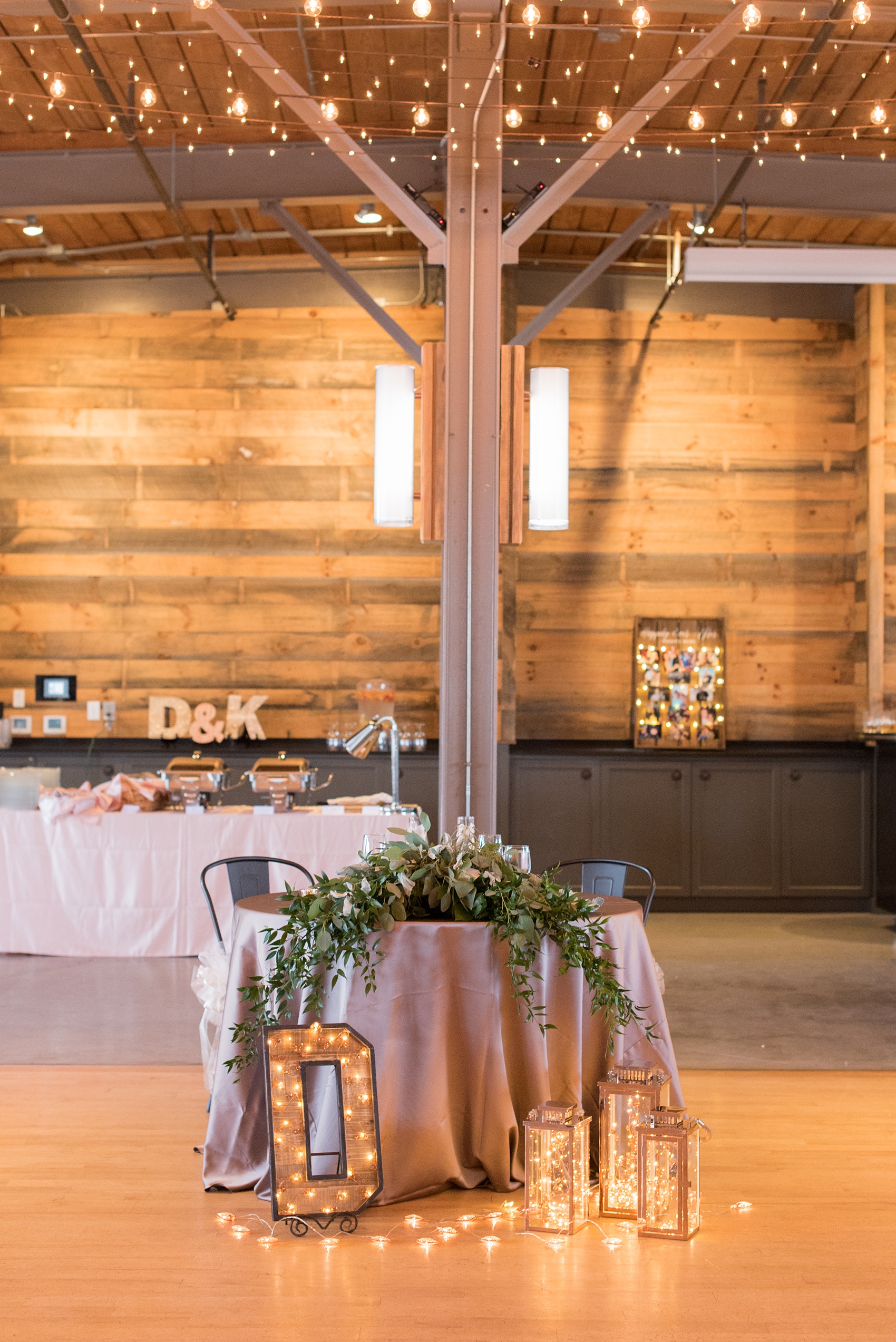 The Rickhouse wedding photos by Mikkel Paige photography in Durham, North Carolina. This urban venue has all the charm of the south for this bride and groom's spring wedding! This picture shows the sweetheart table, dressed in champagne linens with pink napkins, with their monogram letter on the floor. Click to see more from their day! #mikkelpaige #northcarolina #southernwedding #TheRickhouseDurham #rosegoldandpink 