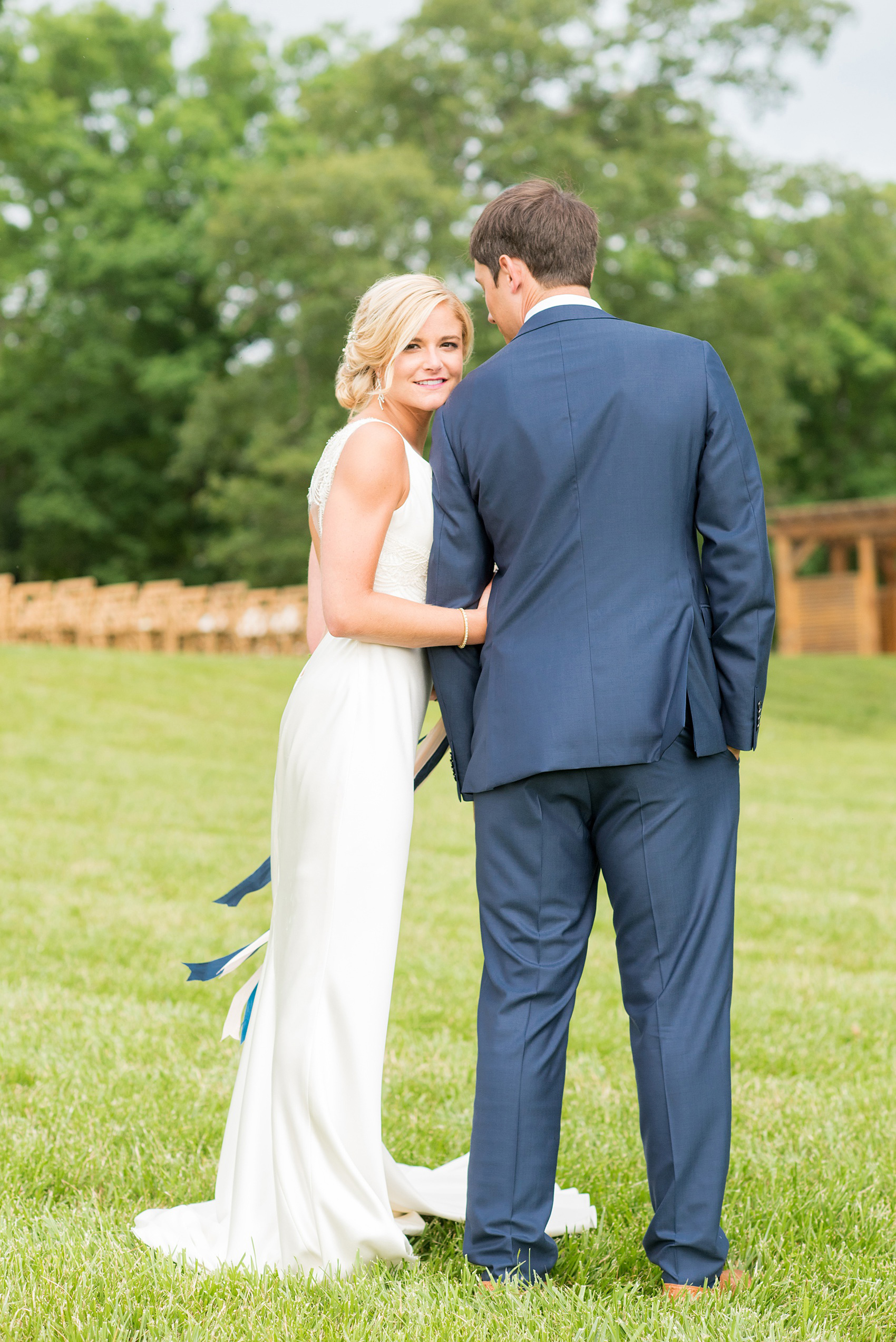 Charlottesville wedding photos by Mikkel Paige Photography. This Virginia venue is perfect for brides and grooms looking for a beautiful farm reception space. It’s green, romantic, and easy to dress up with flowers or keep simple! The bride wore a gorgeous, sexy back cowl neck silk gown by Suzanne Neville and wore her hair in an up-do. The groom wore a navy blue suit and tie and wore a succulent and eucalyptus boutonnière. The bride’s colorful rose, peony and ranunculus bouquet was also dotted with succulents and tied with silk ribbons. Click through for the complete post from this May event at the Lodge at Mount Ida Farm! Planning and design by @vivalevent. #Charlottesville #mountidafarm #lodgeatmountida #CharlottesvilleVA #CharlottesvilleVirginia #Charlottesvillewedding #Charlottesvilleweddingphotographer #mikkelpaige #Vivalevent #brideandgroom #navybluesuit #sexybackweddinggown #backlessweddinggown #suzanneneville #TraditionsbyAnna #WinkHairandMakeup