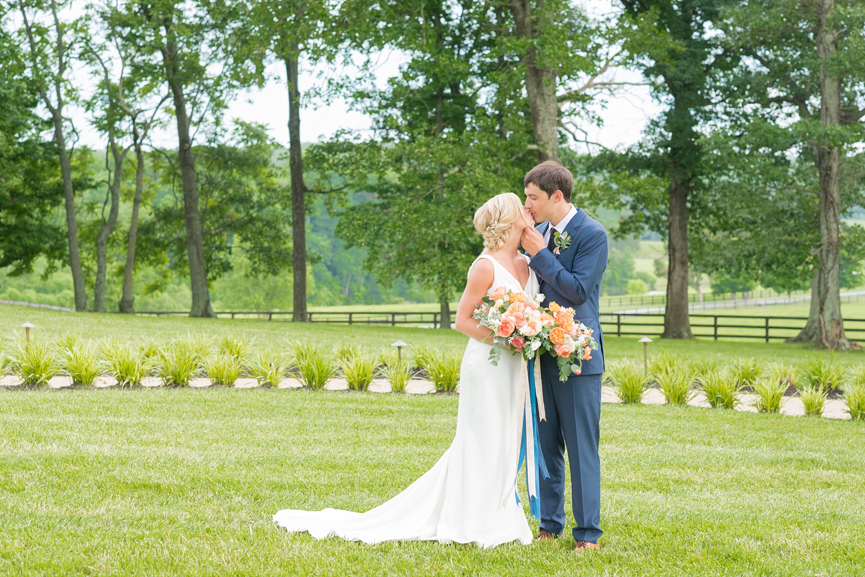 Charlottesville wedding photos by Mikkel Paige Photography. This Virginia venue is perfect for brides and grooms looking for a beautiful farm reception space. It’s green, romantic, and easy to dress up with flowers or keep simple! The bride wore a gorgeous, sexy back cowl neck silk gown by Suzanne Neville and wore her hair in an up-do. The groom wore a navy blue suit and tie and wore a succulent and eucalyptus boutonnière. The bride’s colorful rose, peony and ranunculus bouquet was also dotted with succulents and tied with silk ribbons. Click through for the complete post from this May event at the Lodge at Mount Ida Farm! Planning and design by @vivalevent. #Charlottesville #mountidafarm #lodgeatmountida #CharlottesvilleVA #CharlottesvilleVirginia #Charlottesvillewedding #Charlottesvilleweddingphotographer #mikkelpaige #Vivalevent #brideandgroom #navybluesuit #sexybackweddinggown #backlessweddinggown #suzanneneville #TraditionsbyAnna #WinkHairandMakeup