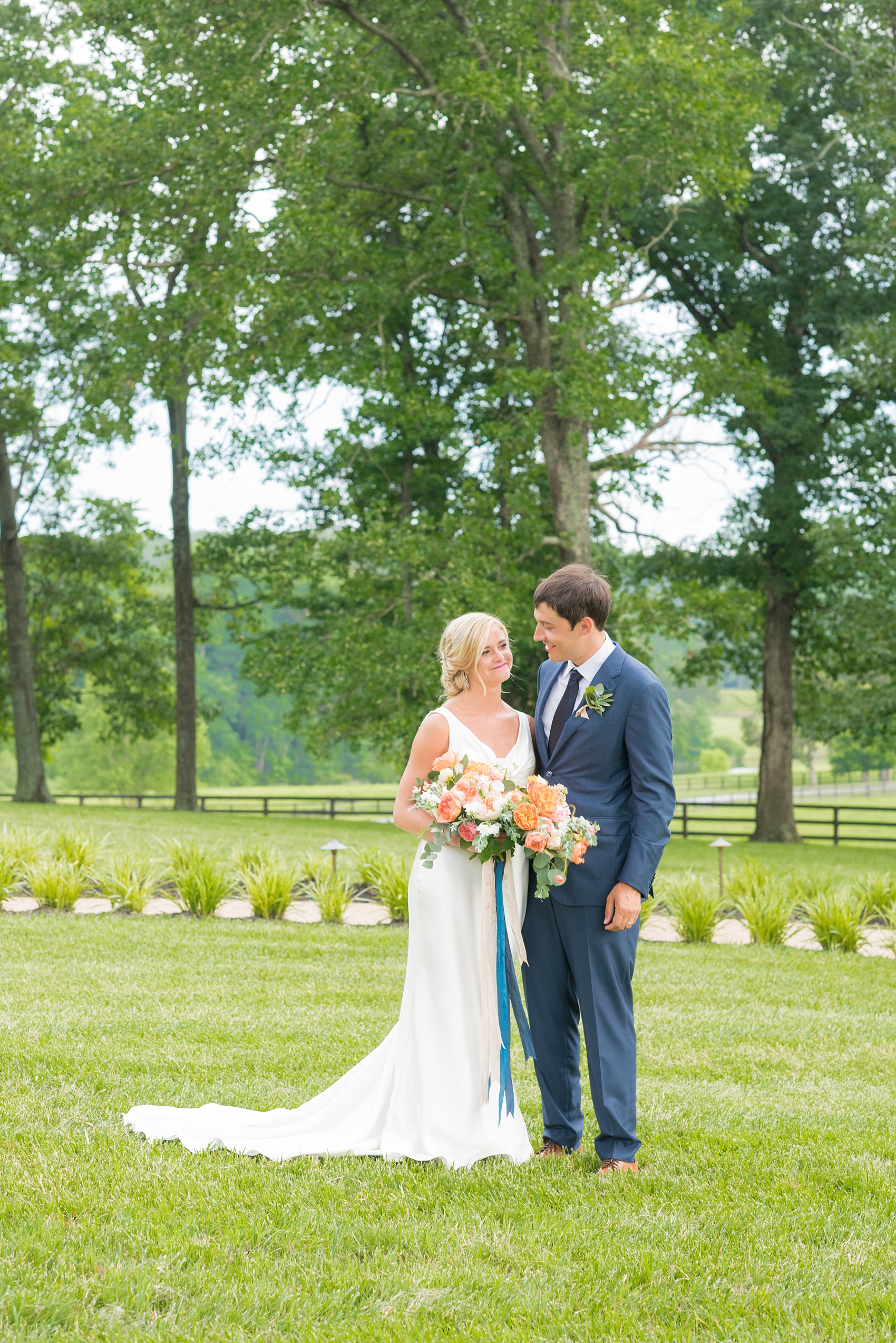 Charlottesville wedding photos by Mikkel Paige Photography. This Virginia venue is perfect for brides and grooms looking for a beautiful farm reception space. It’s green, romantic, and easy to dress up with flowers or keep simple! The bride wore a gorgeous, sexy back cowl neck silk gown by Suzanne Neville and wore her hair in an up-do. The groom wore a navy blue suit and tie and wore a succulent and eucalyptus boutonnière. The bride’s colorful rose, peony and ranunculus bouquet was also dotted with succulents and tied with silk ribbons. Click through for the complete post from this May event at the Lodge at Mount Ida Farm! Planning and design by @vivalevent. #Charlottesville #mountidafarm #lodgeatmountida #CharlottesvilleVA #CharlottesvilleVirginia #Charlottesvillewedding #Charlottesvilleweddingphotographer #mikkelpaige #Vivalevent #brideandgroom #navybluesuit #sexybackweddinggown #backlessweddinggown #suzanneneville #TraditionsbyAnna #WinkHairandMakeup