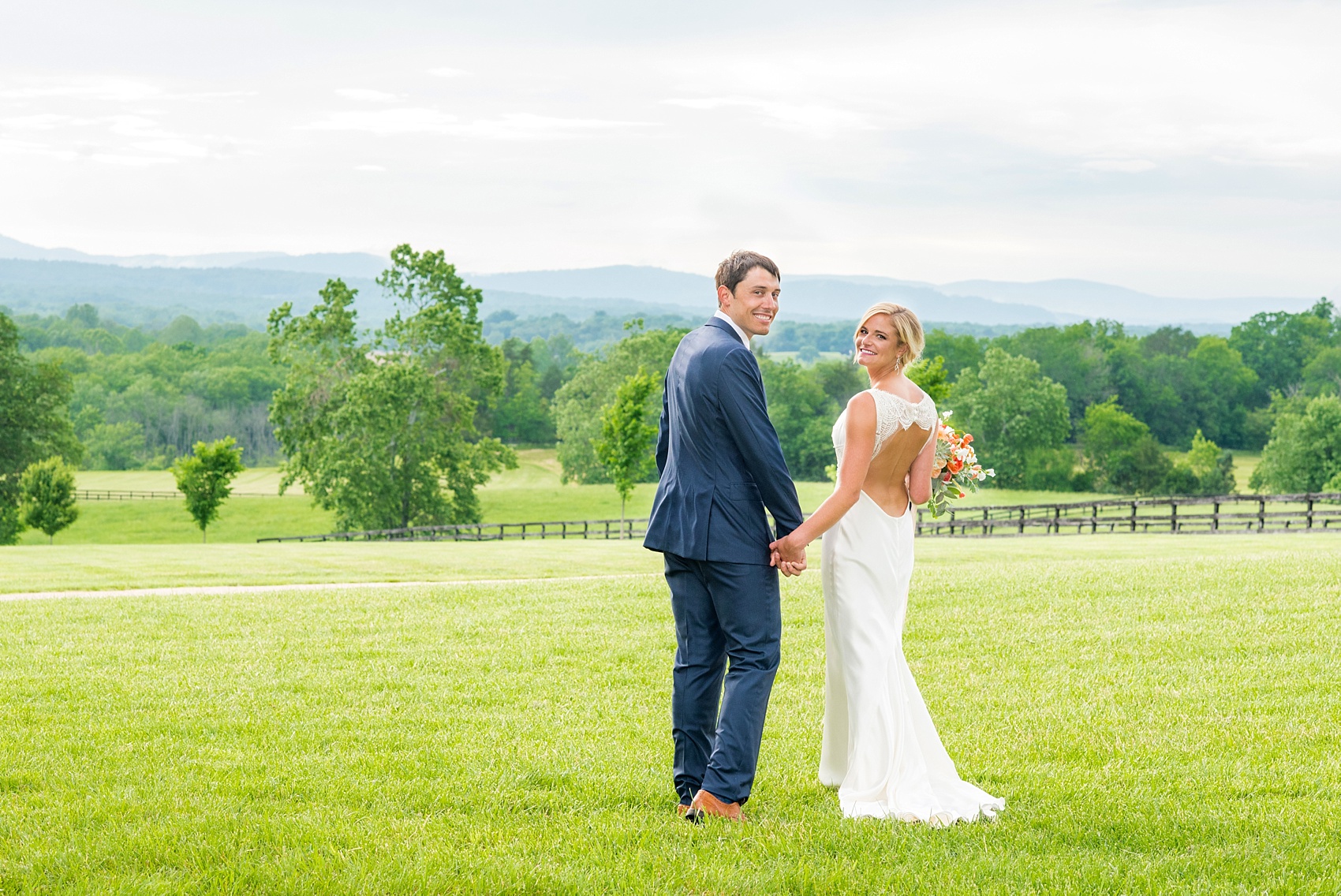 Charlottesville wedding photos by Mikkel Paige Photography. This Virginia venue is perfect for brides and grooms looking for a beautiful farm reception space. It’s green, romantic, and easy to dress up with flowers or keep simple! The bride wore a gorgeous, sexy back cowl neck silk gown by Suzanne Neville and wore her hair in an up-do. The groom wore a navy blue suit and tie and wore a succulent and eucalyptus boutonnière. The bride’s colorful rose, peony and ranunculus bouquet was also dotted with succulents and tied with silk ribbons. Click through for the complete post from this May event at the Lodge at Mount Ida Farm! Planning and design by @vivalevent. #Charlottesville #mountidafarm #lodgeatmountida #CharlottesvilleVA #CharlottesvilleVirginia #Charlottesvillewedding #Charlottesvilleweddingphotographer #mikkelpaige #Vivalevent #brideandgroom #navybluesuit #sexybackweddinggown #backlessweddinggown #suzanneneville #TraditionsbyAnna #WinkHairandMakeup