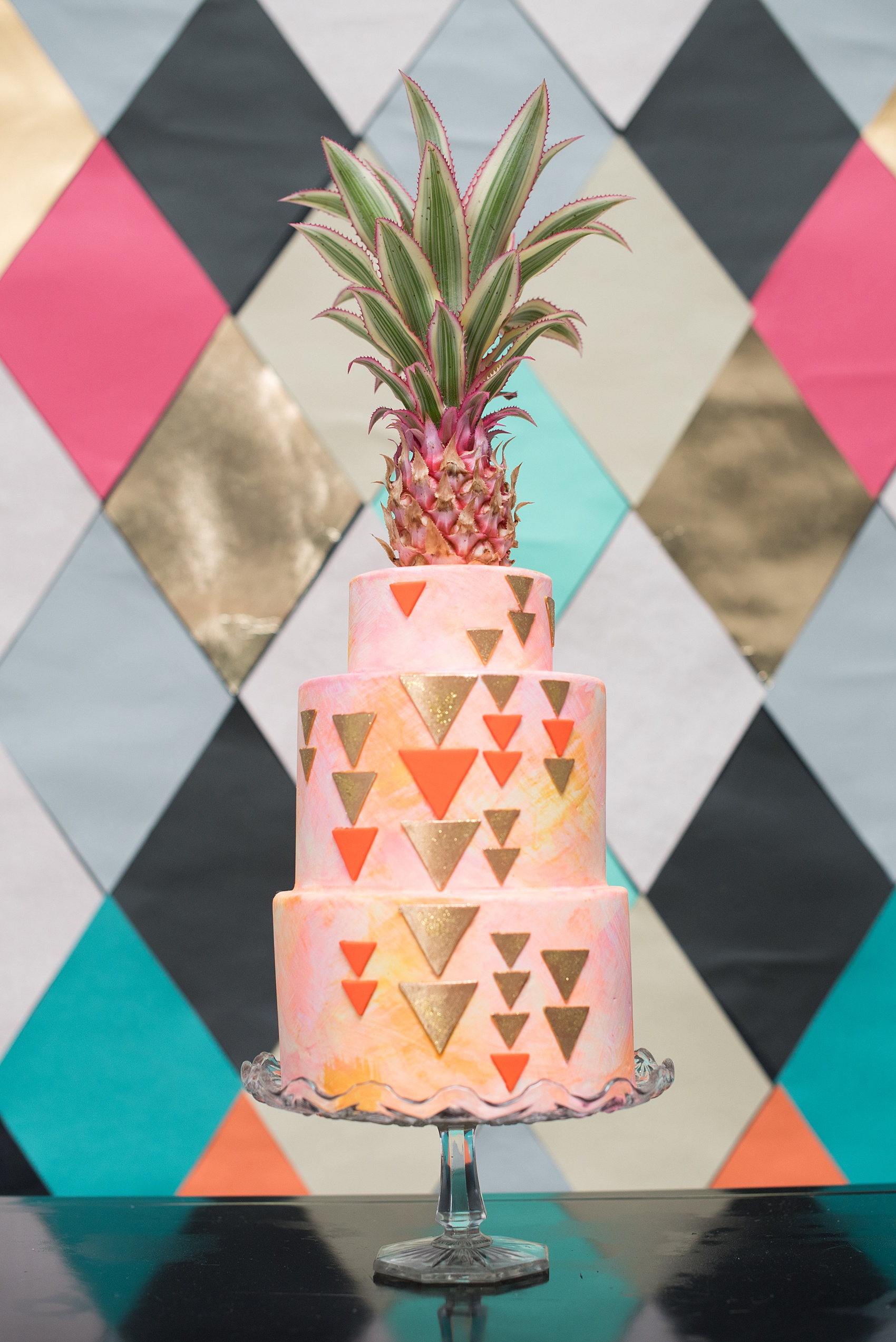 Palm Springs wedding photos for inspiration and ideas for a colorful Mid-Century modern look. Photos by Mikkel Paige Photography, NYC photographer. A custom dessert by Lael Cakes had neon orange details and gold glitter fondant triangles, topped with a pineapple. Click through to see more! Planning by Color Pop Events for a shoot with Love Inc. Mag. #PalmSpringsInspiration #PalmSpringsWedding #Midcenturymodern #customcake #tropicalweddingcake #pineappletopper #minipineapple