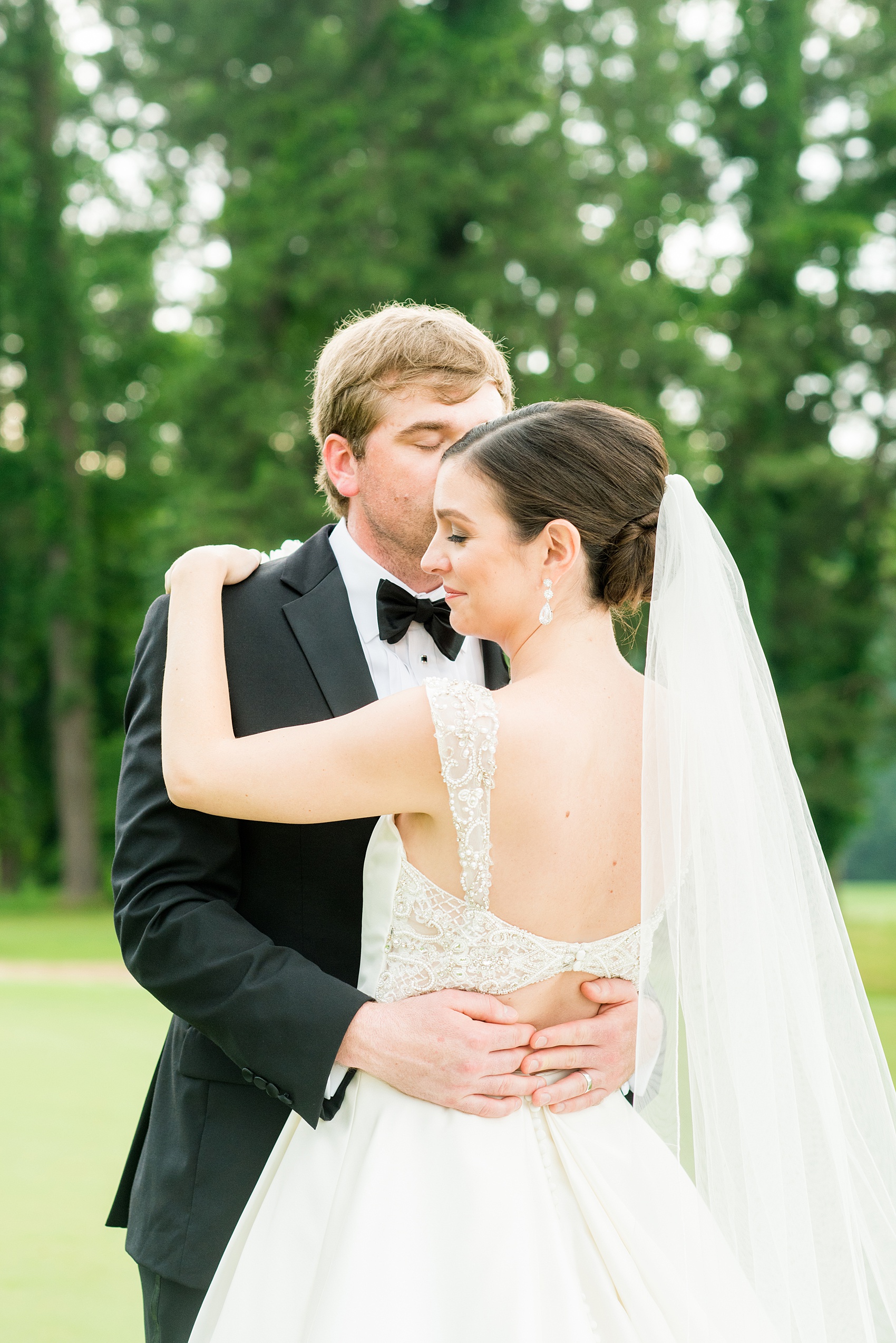 Mikkel Paige Photography pictures of a venue in Durham, North Carolina. The Washington Duke Inn is perfect for a summer wedding! Planning for this beautiful event was by McLean Events. The bride and groom had their pictures taken on the picturesque golf course during golden hour. The back of the bride's gown was incredible and had intricate beading behind her white veil. Hair and Makeup was done by Wink. Click through for more details about this June wedding with peonies! #MikkelPaige #DurhamWeddings #WashingtonDukeInn #DukeWedding #Duke #McLeanEvents #blueandwhitewedding #golfcoursewedding #golfcoursephotos #brideandgroom #winkhairandmakeup