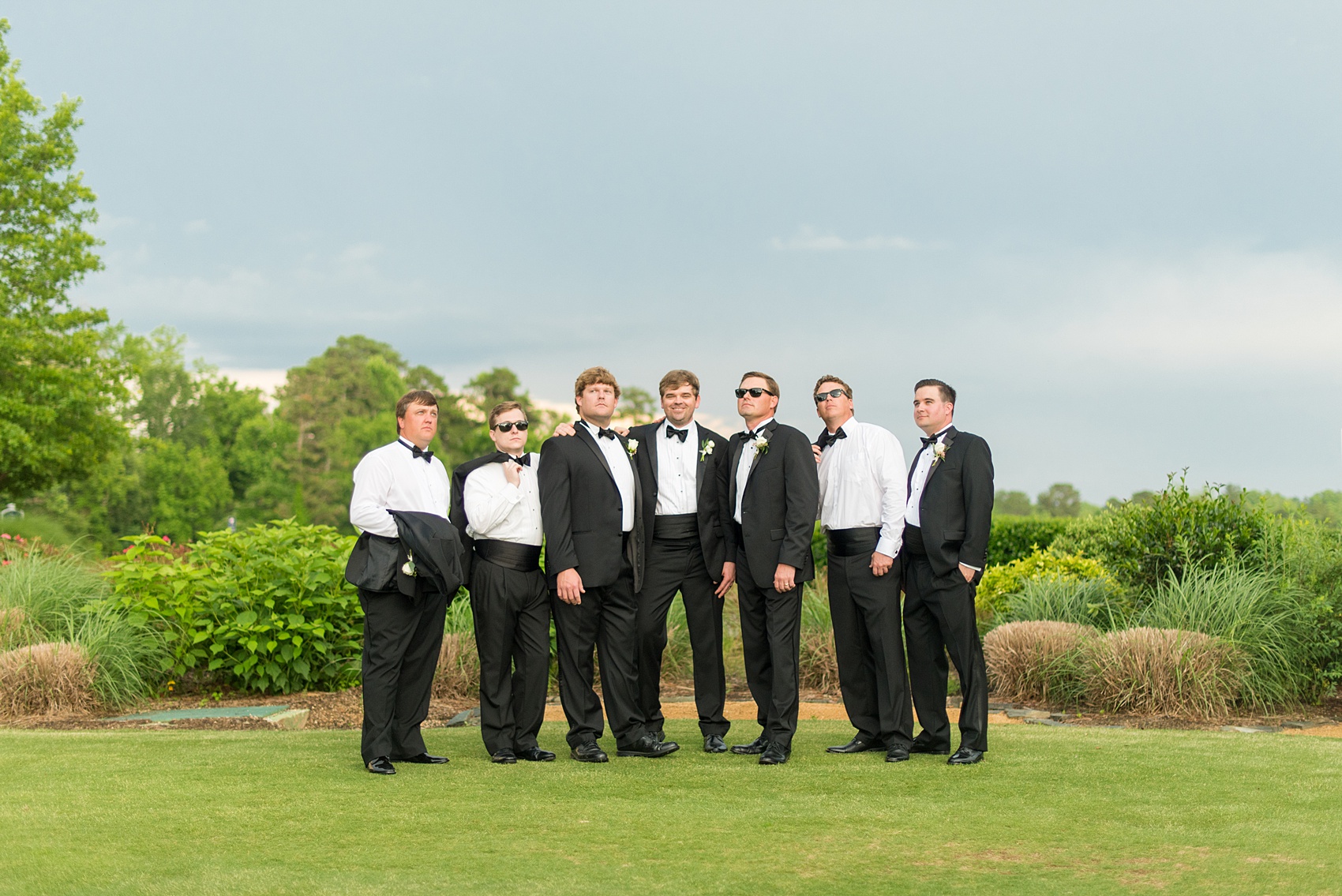 Mikkel Paige Photography pictures of a venue in Durham, North Carolina. The Washington Duke Inn is perfect for a summer wedding! Planning for this beautiful event was by McLean Events. The groom and groomsmen had their pictures taken on the picturesque golf course. They wore classic black tuxedos and bow ties. Click through for more details about this June wedding! #MikkelPaige #DurhamWeddings #WashingtonDukeInn #DukeWedding #Duke #McLeanEvents #blueandwhitewedding #golfcoursewedding #golfcoursephotos #groomsmen #weddingparty #blacktuxedos
