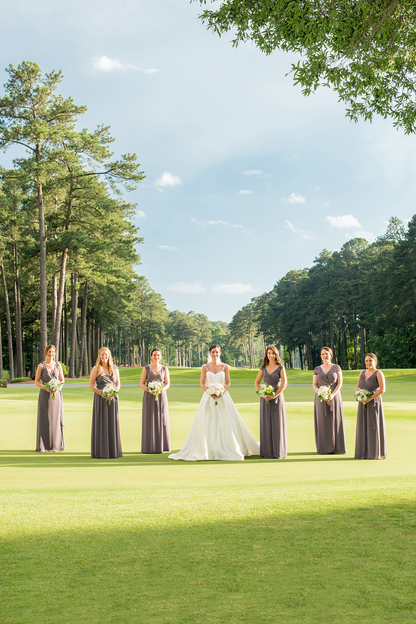 Mikkel Paige Photography pictures of a venue in Durham, North Carolina. The Washington Duke Inn is perfect for a summer wedding! Planning for this beautiful event was by McLean Events. The bride and her bridesmaids had their pictures taken on the golf course during golden hour. They wore grey chiffon gowns and carried white and pink bouquets. Hair and Makeup was done by Wink. Click through for more details about this June wedding with peonies! #MikkelPaige #DurhamWeddings #WashingtonDukeInn #DukeWedding #Duke #McLeanEvents #blueandwhitewedding #golfcoursewedding #golfcoursephotos #brideandgroom #bridalparty #weddingparty #greybridesmaids #peonybouquet