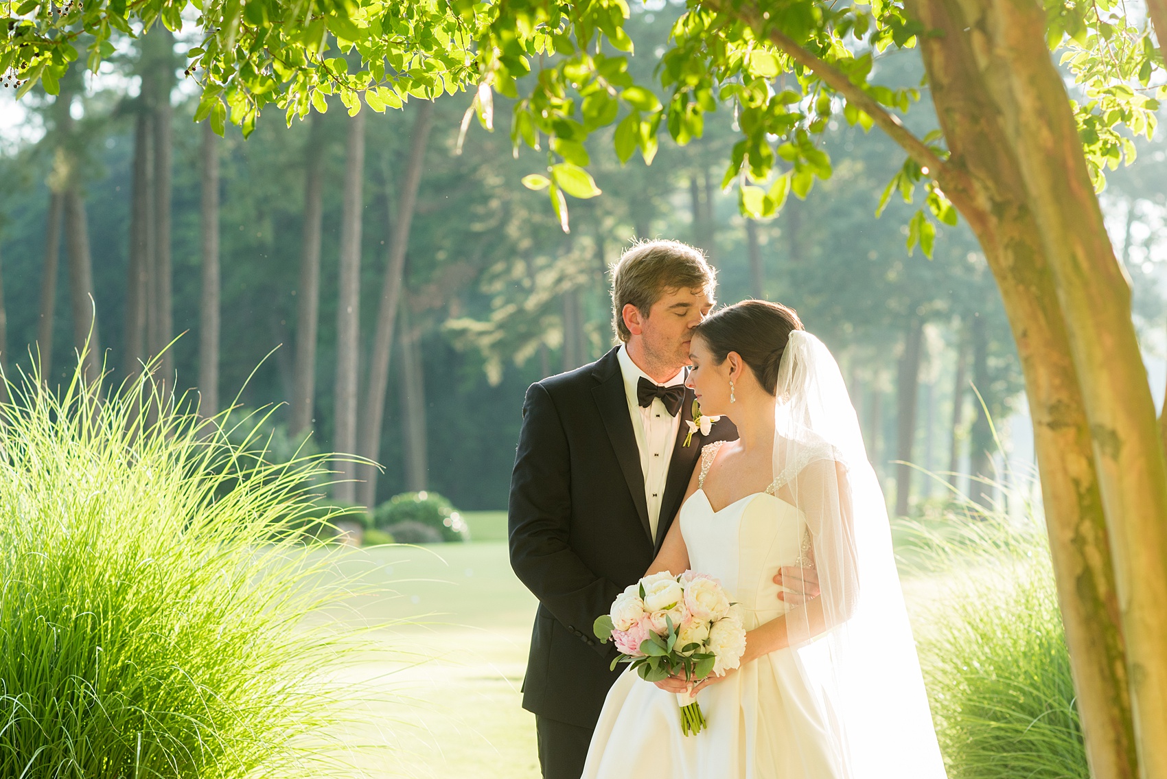 Mikkel Paige Photography pictures of a venue in Durham, North Carolina. The Washington Duke Inn is perfect for a summer wedding! Planning for this beautiful event was by McLean Events. The bride and groom had their pictures taken on the picturesque golf course during golden hour. The back of the bride's gown was incredible and had intricate beading behind her white veil. Hair and Makeup was done by Wink. Click through for more details about this June wedding with peonies! #MikkelPaige #DurhamWeddings #WashingtonDukeInn #DukeWedding #Duke #McLeanEvents #blueandwhitewedding #golfcoursewedding #golfcoursephotos #brideandgroom #winkhairandmakeup