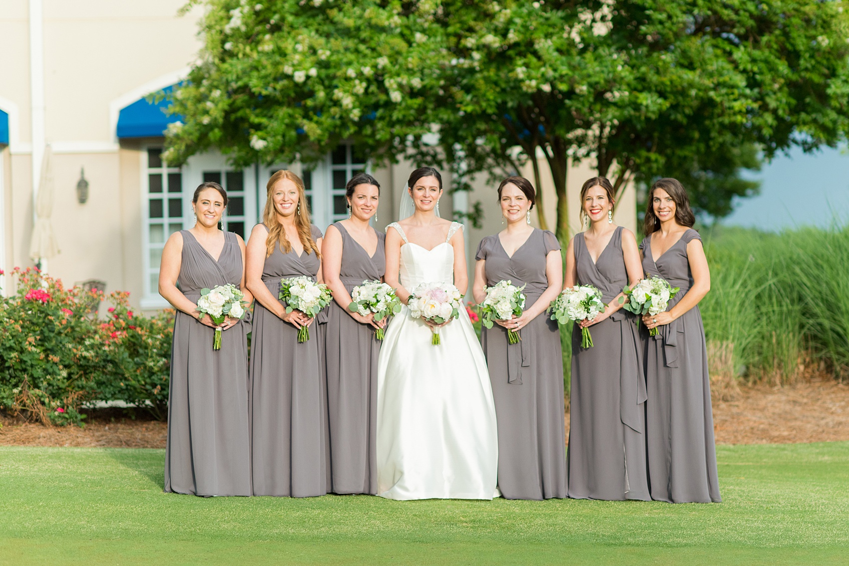 Mikkel Paige Photography pictures of a venue in Durham, North Carolina. The Washington Duke Inn is perfect for a summer wedding! Planning for this beautiful event was by McLean Events. The bride and her bridesmaids had their pictures taken on the golf course during golden hour. They wore grey chiffon gowns and carried white and pink bouquets. Hair and Makeup was done by Wink. Click through for more details about this June wedding with peonies! #MikkelPaige #DurhamWeddings #WashingtonDukeInn #DukeWedding #Duke #McLeanEvents #blueandwhitewedding #golfcoursewedding #golfcoursephotos #brideandgroom #bridalparty #weddingparty #greybridesmaids #peonybouquet