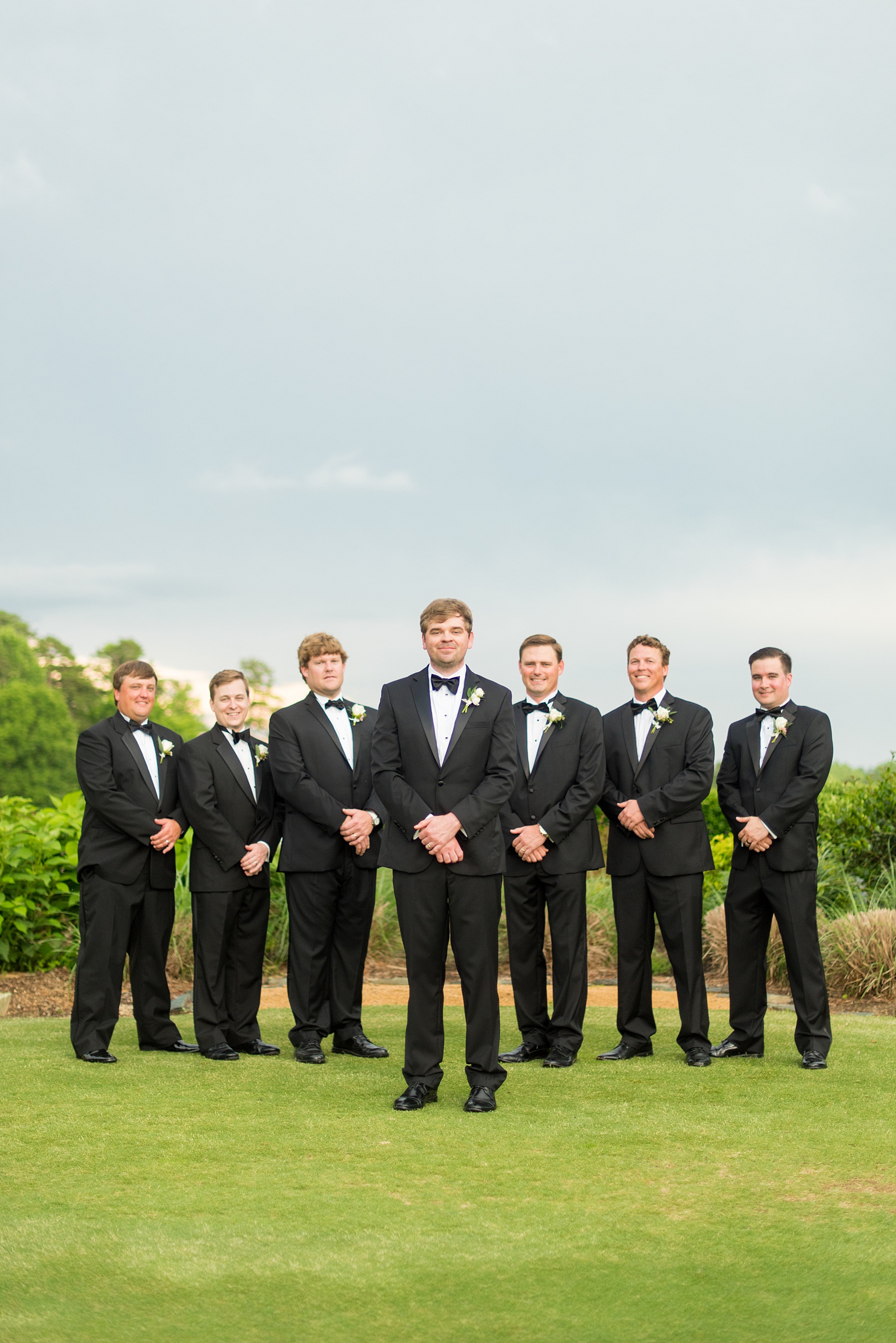 Mikkel Paige Photography pictures of a venue in Durham, North Carolina. The Washington Duke Inn is perfect for a summer wedding! Planning for this beautiful event was by McLean Events. The groom and groomsmen had their pictures taken on the picturesque golf course. They wore classic black tuxedos and bow ties. Click through for more details about this June wedding! #MikkelPaige #DurhamWeddings #WashingtonDukeInn #DukeWedding #Duke #McLeanEvents #blueandwhitewedding #golfcoursewedding #golfcoursephotos #groomsmen #weddingparty #blacktuxedos