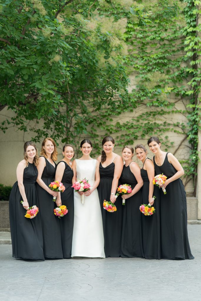 Manhattan Central Park wedding photos by Mikkel Paige Photography at Loeb Boathouse venue. These ceremony and reception pictures show a timeless couple having fun at their colorful day with guests who traveled in from abroad. The bridesmaids wore mismatched black chiffon gowns and held colorful summer flowers for a June celebration. Click through for the complete post! #CentralParkWeddingVenues #NYCweddingphotographer #NYCwedding #SummerWedding #BlackBridesmaidsDresses