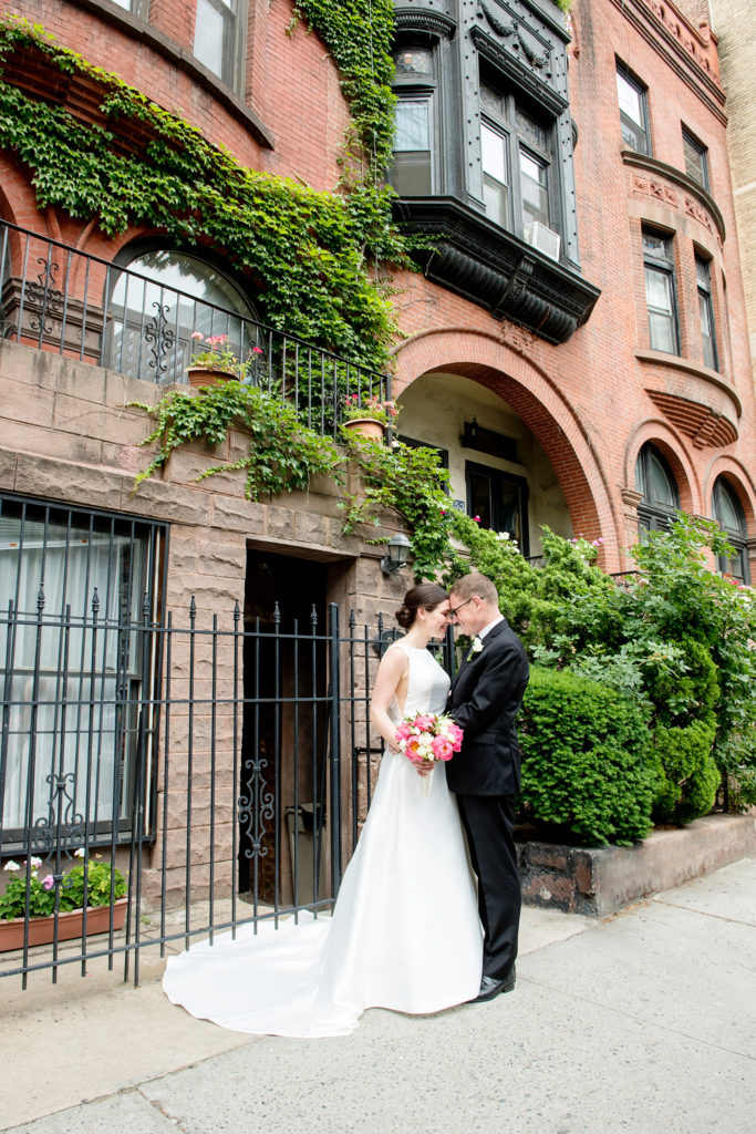 Manhattan Central Park wedding photos by Mikkel Paige Photography at Loeb Boathouse venue. These bride and groom pictures show a timeless couple having fun on their colorful day in this iconic NYC landmark and Upper West Side. The bride held a pink peony bouquet for their June celebration and wore a boat-neck gown with buttons down the back. A brownstone with creeping ivy completed the image. Click through for the complete post! #CentralParkWedding #CityWedding #brideandgroom