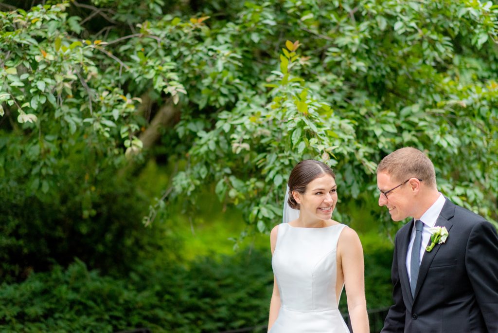 Manhattan Central Park wedding photos by Mikkel Paige Photography at Loeb Boathouse venue. These reception pictures show a timeless couple having fun at their colorful day in this iconic NYC landmark. The bride held a pink peony bouquet for their June celebration and wore a boat-neck gown with buttons down the back and the groom a black suit. Click through for the complete post! #CentralParkWeddingVenues #NYCweddingphotographer #NYCwedding #SummerWedding #CentralParkPhotos #NYbrideandgroom