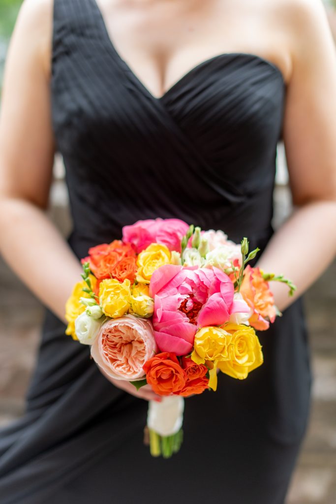 Manhattan Central Park wedding photos by Mikkel Paige Photography at Loeb Boathouse venue. These ceremony and reception pictures show a timeless couple having fun at their colorful day with guests who traveled in from abroad. The bridesmaids wore mismatched black chiffon gowns and held colorful summer flowers for a June celebration. Click through for the complete post! #CentralParkWeddingVenues #NYCweddingphotographer #NYCwedding #SummerWedding #BlackBridesmaidsDresses