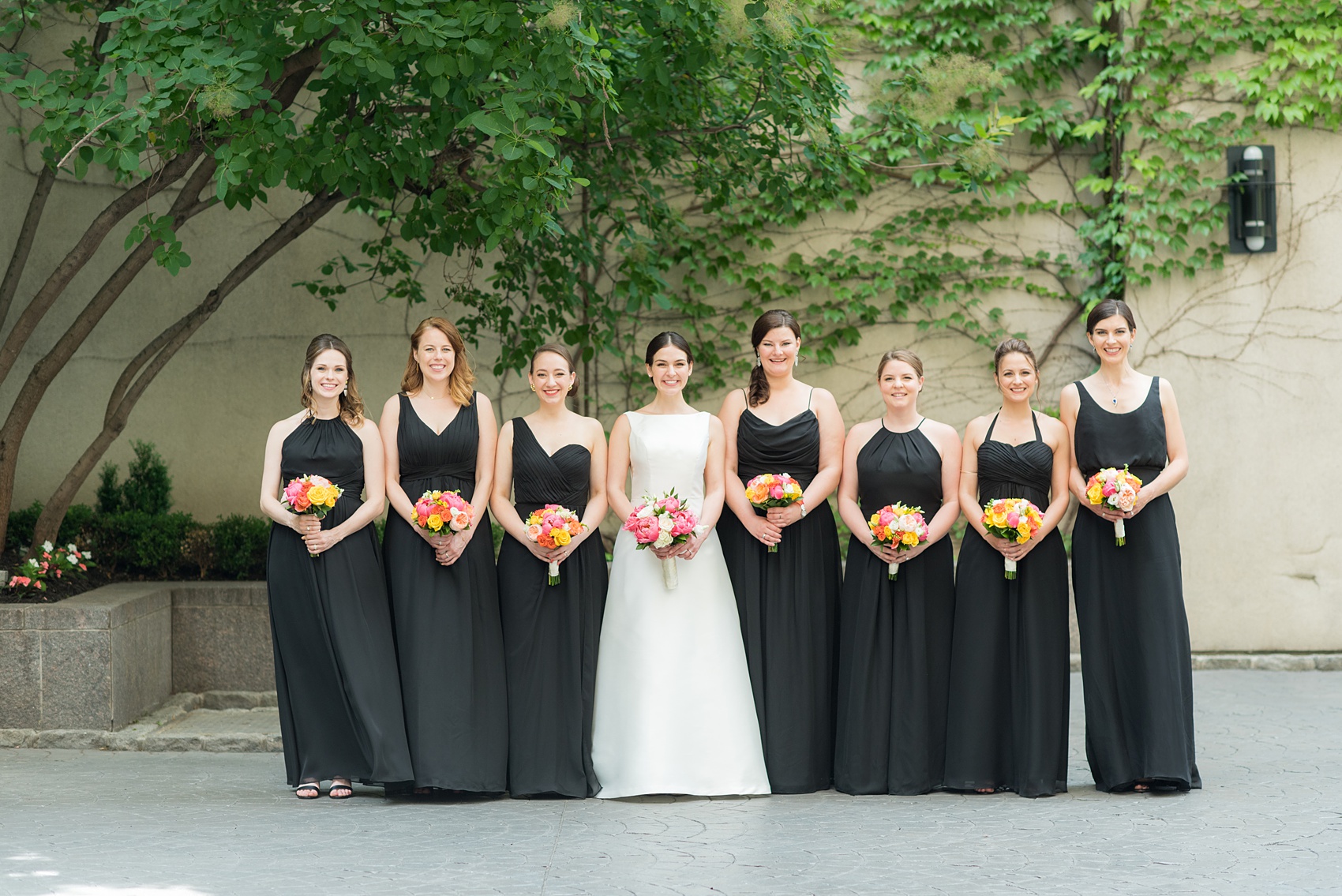 Manhattan Central Park wedding photos by Mikkel Paige Photography at Loeb Boathouse venue. These ceremony and reception pictures show a timeless couple having fun at their colorful day with guests who traveled in from abroad. The bride and groom took their pictures on the Upper West Side with their bridesmaids in mismatched black chiffon gowns, holding colorful summer flowers for their June celebration. Click through for the complete post! #CentralParkWeddingVenues #NYCweddingphotographer #NYCwedding #SummerWedding #BlackBridesmaidsDresses