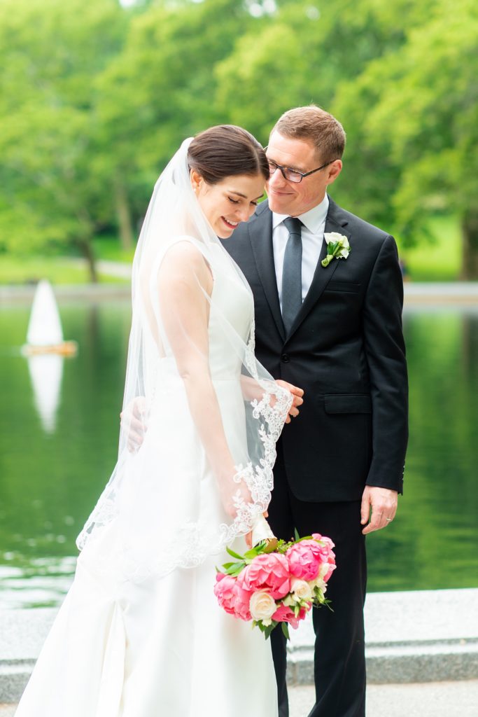 Manhattan Central Park wedding photos by Mikkel Paige Photography at Loeb Boathouse venue. These reception pictures show a timeless couple having fun at their colorful day in this iconic NYC landmark. The bride held a pink peony bouquet for their June celebration and wore a boat-neck gown with buttons down the back and the groom a black suit. Click through for the complete post! #CentralParkWeddingVenues #NYCweddingphotographer #NYCwedding #SummerWedding #CentralParkPhotos #NYbrideandgroom