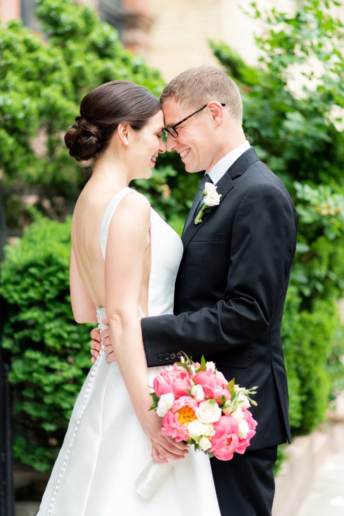 Manhattan Central Park wedding photos by Mikkel Paige Photography at Loeb Boathouse venue. These reception pictures show a timeless couple having fun at their colorful day in this iconic NYC landmark. The bride held a pink peony bouquet for their June celebration and wore a boat-neck gown with buttons down the back and the groom a black suit. Click through for the complete post! #CentralParkWeddingVenues #NYCweddingphotographer #NYCwedding #SummerWedding #CentralParkPhotos #NYbrideandgroom