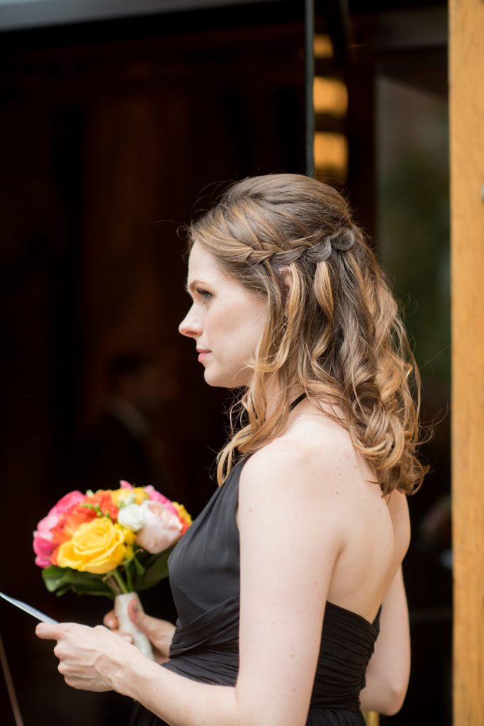 Manhattan Central Park wedding photos by Mikkel Paige Photography at Loeb Boathouse venue. The bridesmaid wore a black chiffon dress and had a cascading waterfall braid half-up do. She held colorful summer flowers for a June celebration. Click through for the complete post! #CentralParkWeddingVenues #NYCweddingphotographer #NYCwedding #SummerWedding #BlackBridesmaidsDresses #bridesmaidhairstyle #braids #waterfallbraids #cascadingbraids