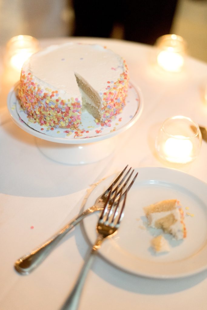 Manhattan Central Park wedding photos by Mikkel Paige Photography at Loeb Boathouse venue. The reception was by the lake and Bethesda Terrace for a June celebration. Guests, who traveled in from near and far, watched the newlyweds cut a simple small buttercream cake with confetti sprinkles from Trader Joe's. Click through for the complete post! #CentralParkWeddingVenues #NYCwedding #SummerWedding #weddingreception #brideandgroom #weddingcake #TraderJoes #simplecake #confettisprinkles #cakecutting