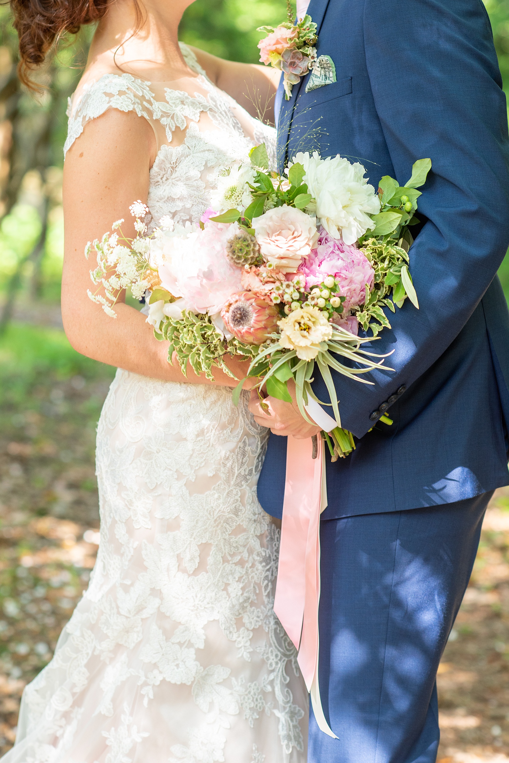 A summer wedding at Olde Mill Inn, NJ. Photos by Mikkel Paige Photography for an event with light pink and blue details. This New Jersey venue is a great option for something not too far from NYC. The bride carried a bouquet of King Protea, peonies, scabiosa pods and assorted garden flowers. The stems were wrapped with colorful ribbon and had a special locket charm on it with photos of family members who had passed away. Click through for their complete wedding recap! #OldeMillInn #NJwedding #NJweddingphotographer #mikkelpaige #NewJerseyWeddingVenue #NewJerseyWedding #CrossEstateGardens #weddingdetails #weddingbouquet #bouquetcharm #peonies #protea