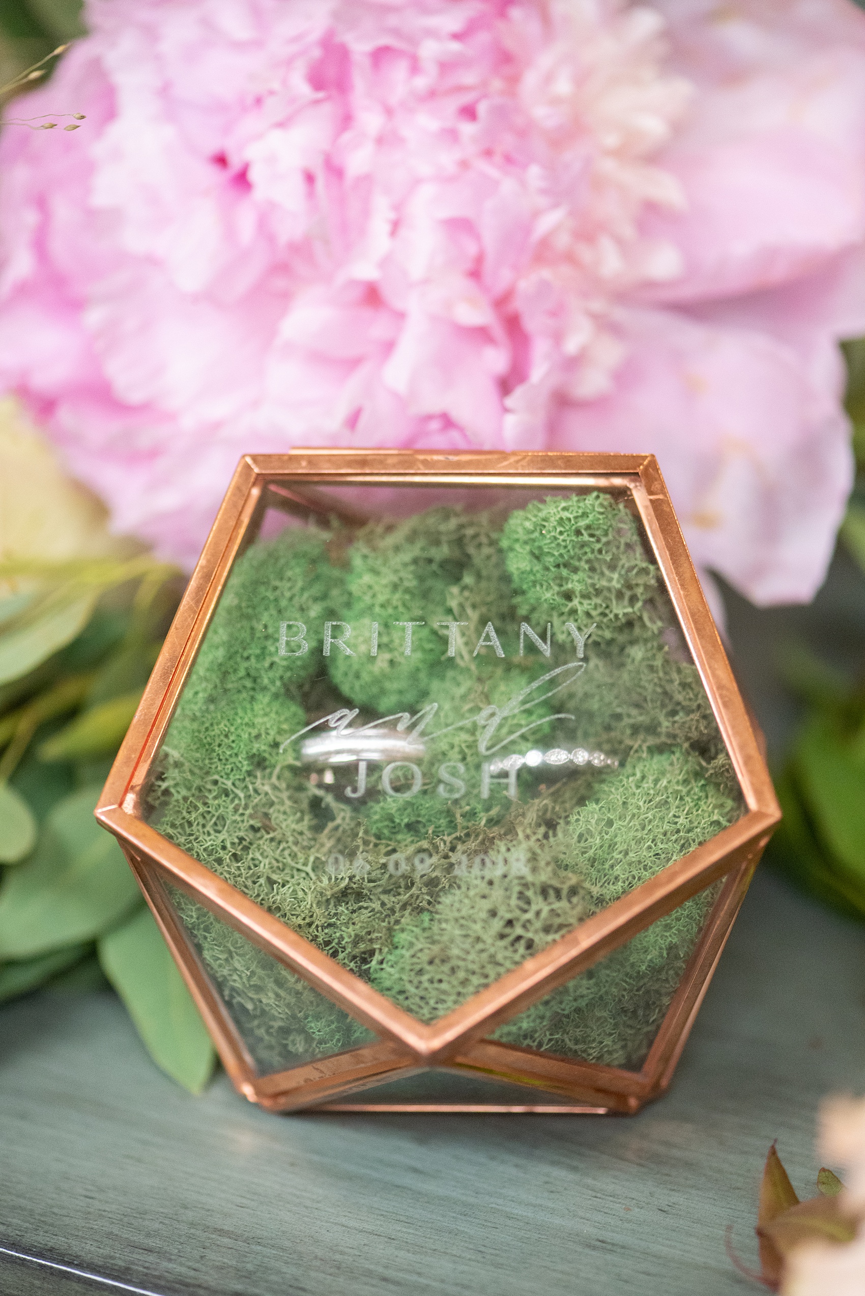 A summer wedding at Olde Mill Inn, NJ. Photos by Mikkel Paige Photography for an event with light pink and blue details. This New Jersey venue is a great option for something not too far from NYC. The bride wanted a Midsummer Night’s Dream theme and carried that out with garden details, like this glass ring box engraved with their names, filled with green moss and their bands. Click through for their complete wedding recap! #OldeMillInn #NJwedding #NJweddingphotographer #mikkelpaige #NewJerseyWeddingVenue #NewJerseyWedding #CrossEstateGardens #weddingdetails #ringbox #midsummernightsdream