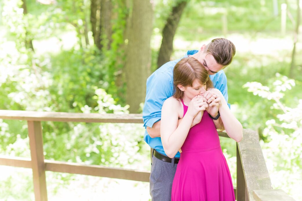 Maryland summer engagement photos by Mikkel Paige Photography. This couple wore semi-formal outfits with the bride in a beautiful, sexy back fuchsia pink gown and the groom in a blue button down and grey pants. Their elegant outdoor park pictures were perfect for the season! Click through to see more from their romantic pictures in the woods! #mikkelpaige #summerengagementphotos #marylandengagementphotos #marylandweddingphotographer #parkengagementsession #engagementphotooutfitideas #engagementphotos #savethedatephotos