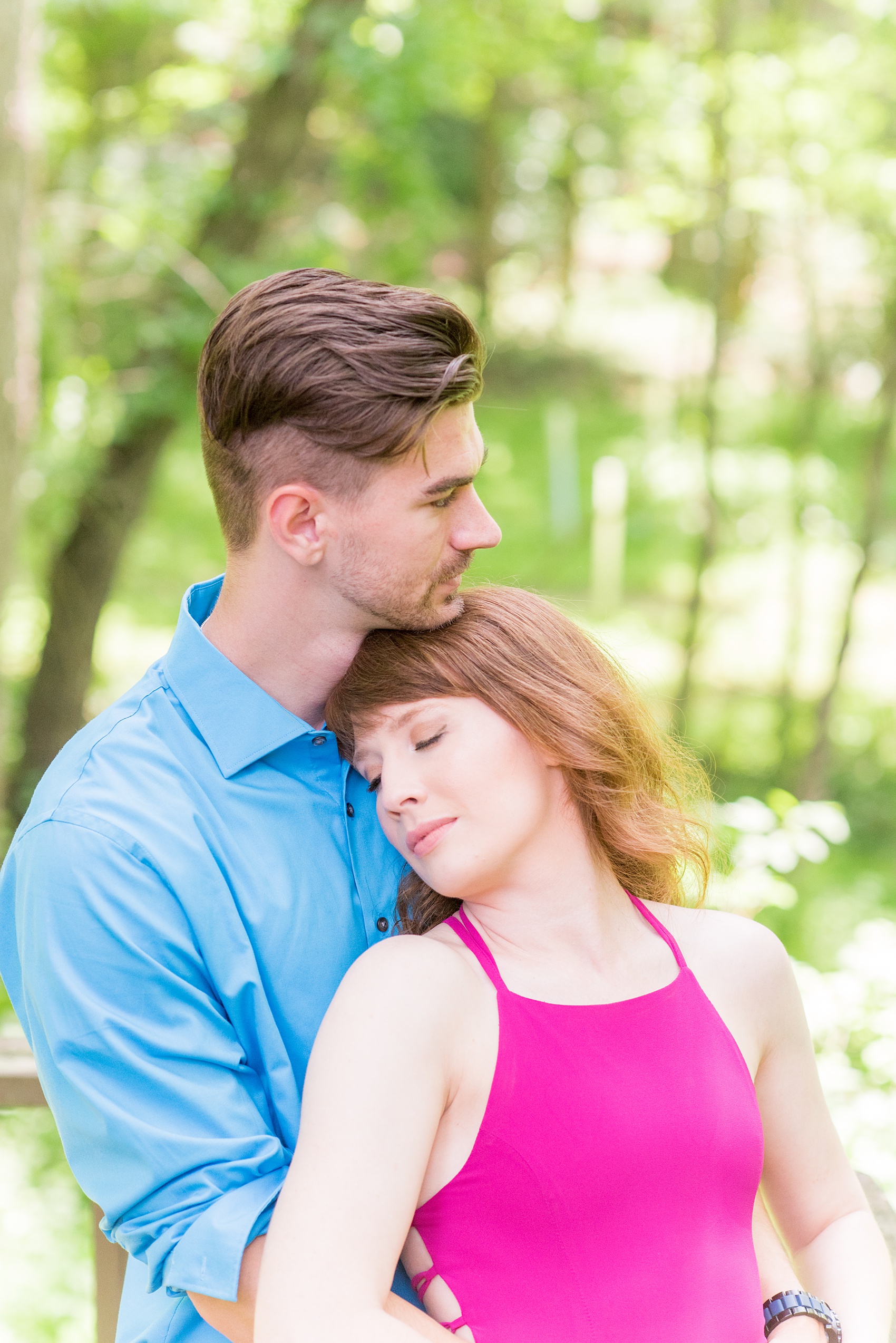 Maryland summer engagement photos by Mikkel Paige Photography. This couple wore semi-formal outfits with the bride in a beautiful, sexy back fuchsia pink gown and the groom in a blue button down and grey pants. Their elegant outdoor park pictures were perfect for the season! Click through to see more from their romantic pictures in the woods! #mikkelpaige #summerengagementphotos #marylandengagementphotos #marylandweddingphotographer #parkengagementsession #engagementphotooutfitideas #engagementphotos #savethedatephotos 