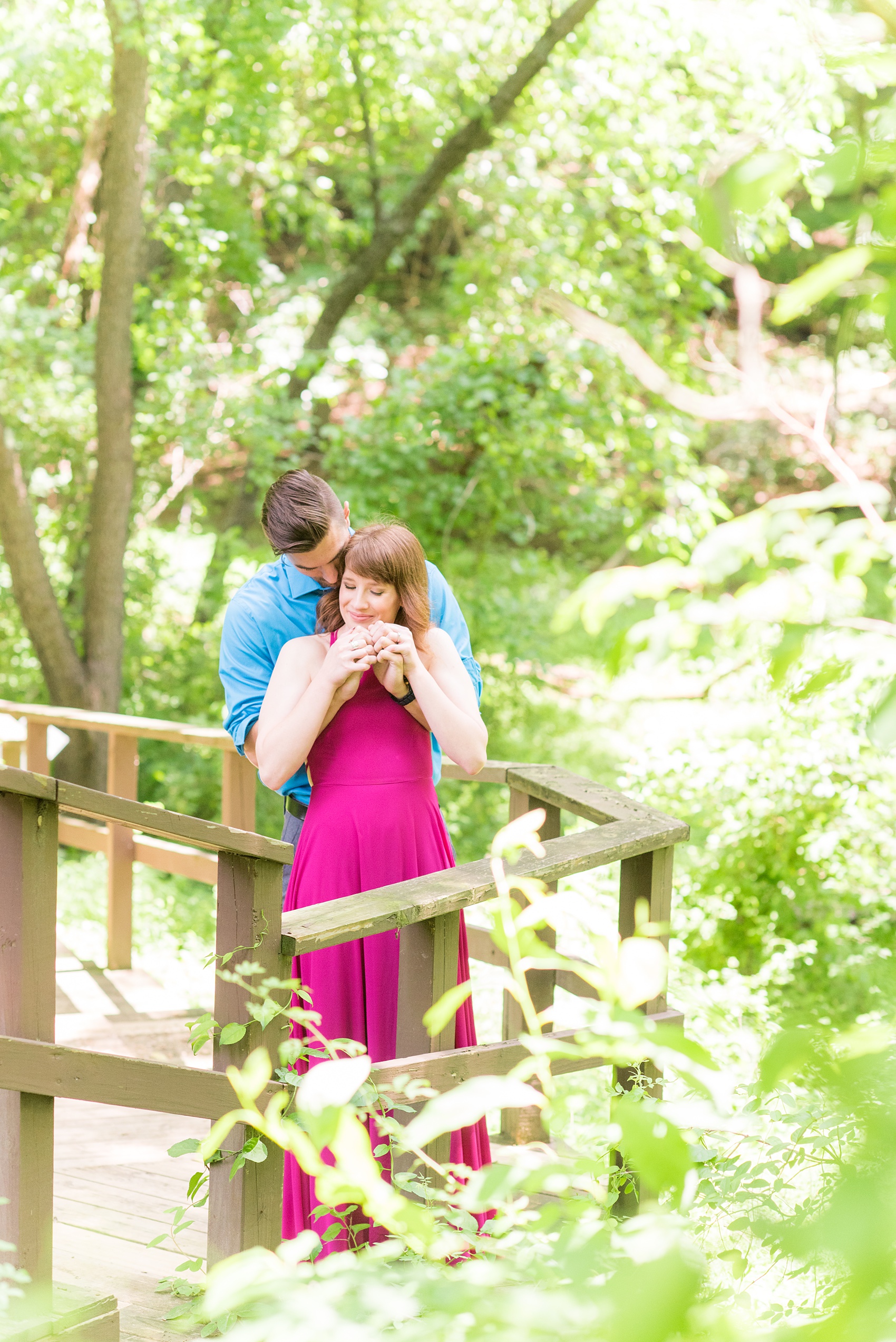 Maryland summer engagement photos by Mikkel Paige Photography. This couple wore semi-formal outfits with the bride in a beautiful, sexy back fuchsia pink gown and the groom in a blue button down and grey pants. Their elegant outdoor park pictures were perfect for the season! Click through to see more from their romantic pictures in the woods! #mikkelpaige #summerengagementphotos #marylandengagementphotos #marylandweddingphotographer #parkengagementsession #engagementphotooutfitideas #engagementphotos #savethedatephotos 