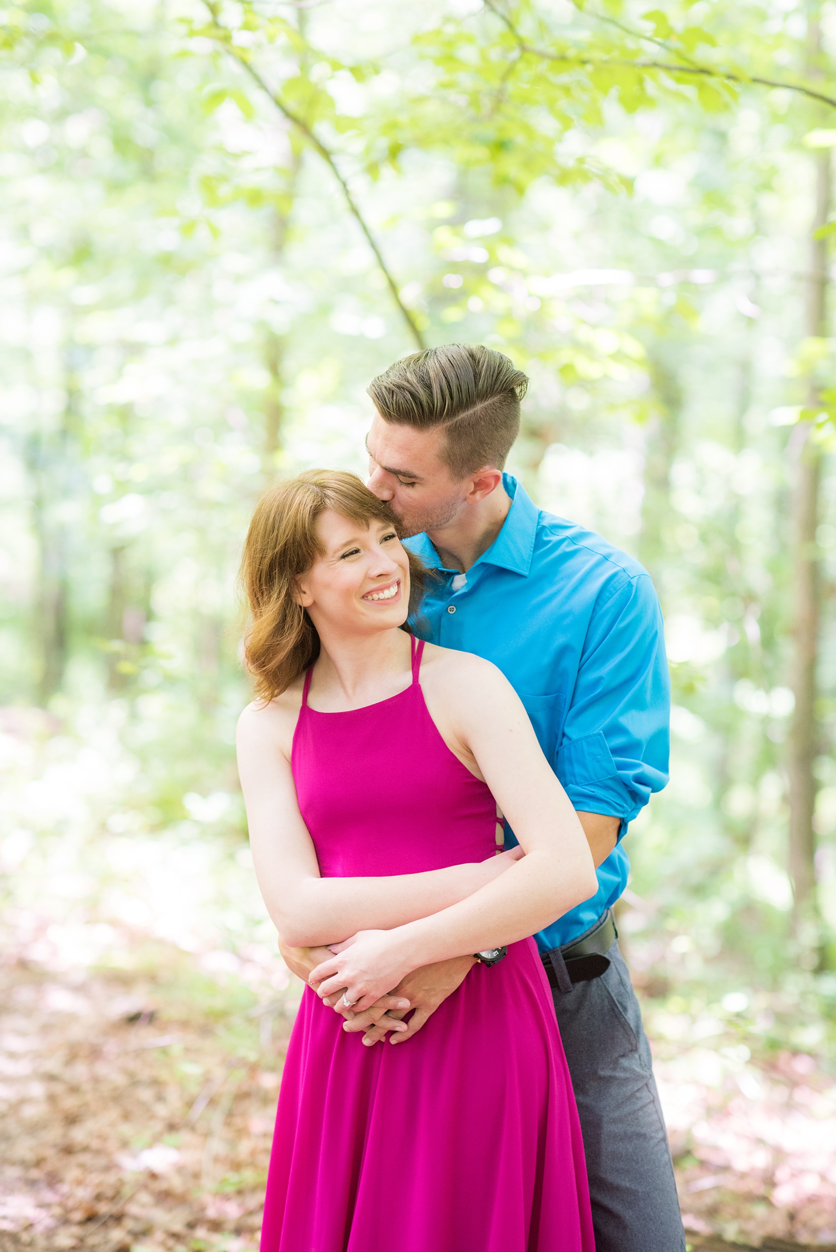 Maryland summer engagement photos by Mikkel Paige Photography. This couple wore semi-formal outfits with the bride in a beautiful, sexy back fuchsia pink gown and the groom in a blue button down and grey pants. Their elegant outdoor park pictures were perfect for the season! Click through to see more from their romantic pictures in the woods! #mikkelpaige #summerengagementphotos #marylandengagementphotos #marylandweddingphotographer #parkengagementsession #engagementphotooutfitideas #engagementphotos #savethedatephotos 