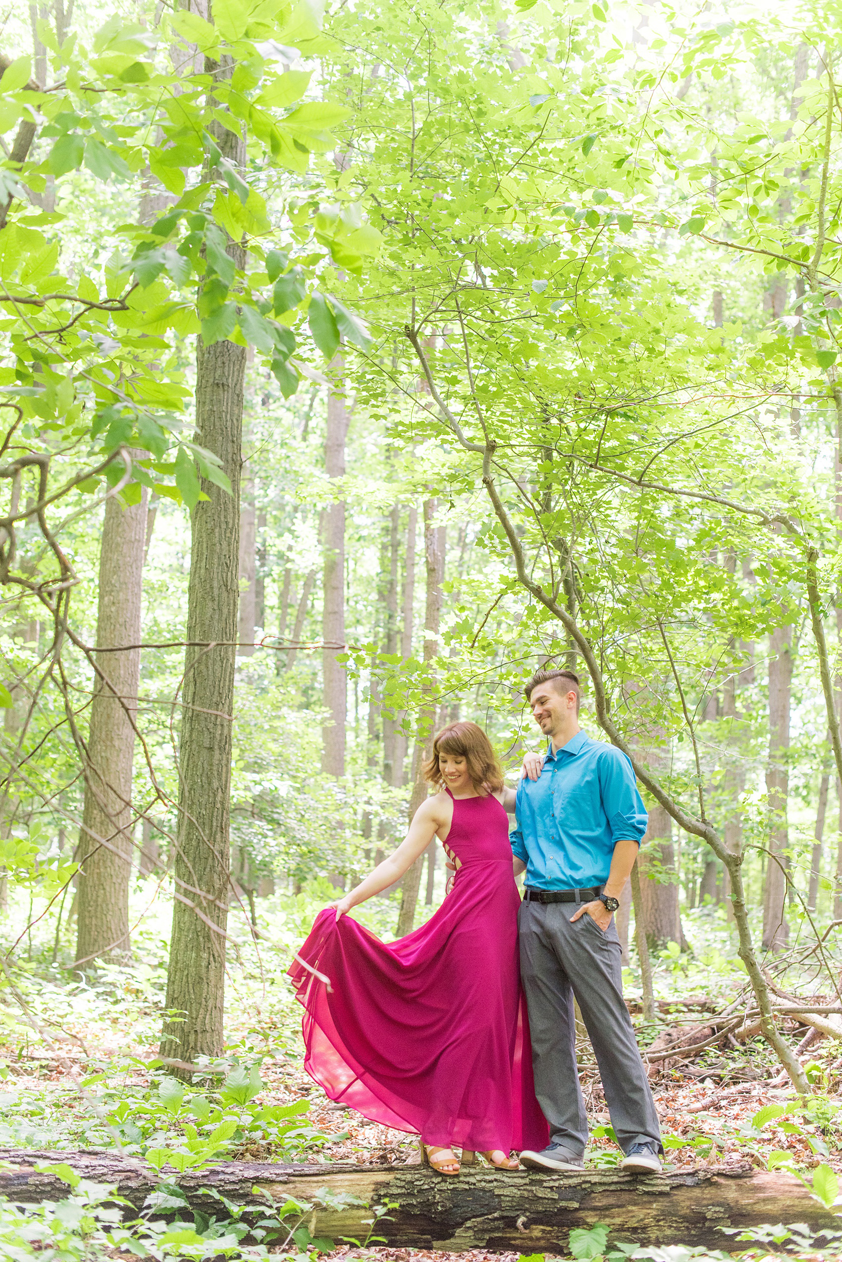 Maryland summer engagement photos by Mikkel Paige Photography. This couple wore semi-formal outfits with the bride in a beautiful, sexy back fuchsia pink gown and the groom in a blue button down and grey pants. Their elegant outdoor park pictures were perfect for the season! Click through to see more from their romantic pictures in the woods! #mikkelpaige #summerengagementphotos #marylandengagementphotos #marylandweddingphotographer #parkengagementsession #engagementphotooutfitideas #engagementphotos #savethedatephotos 