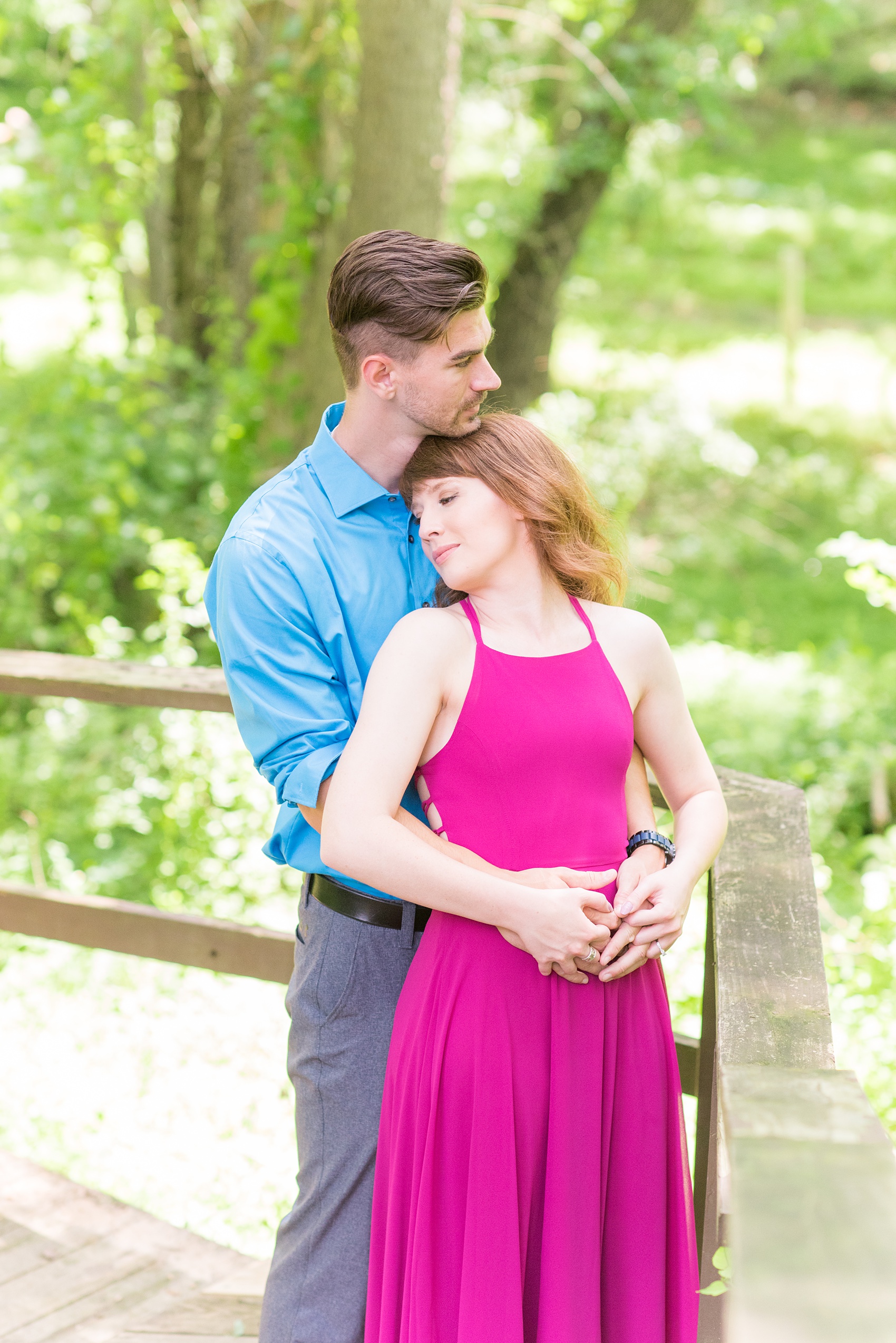 Maryland summer engagement photos by Mikkel Paige Photography. This couple wore semi-formal outfits with the bride in a beautiful, sexy back fuchsia pink gown and the groom in a blue button down and grey pants. Their elegant outdoor park pictures were perfect for the season! Click through to see more from their romantic pictures in the woods! #mikkelpaige #summerengagementphotos #marylandengagementphotos #marylandweddingphotographer #parkengagementsession #engagementphotooutfitideas #engagementphotos #savethedatephotos 