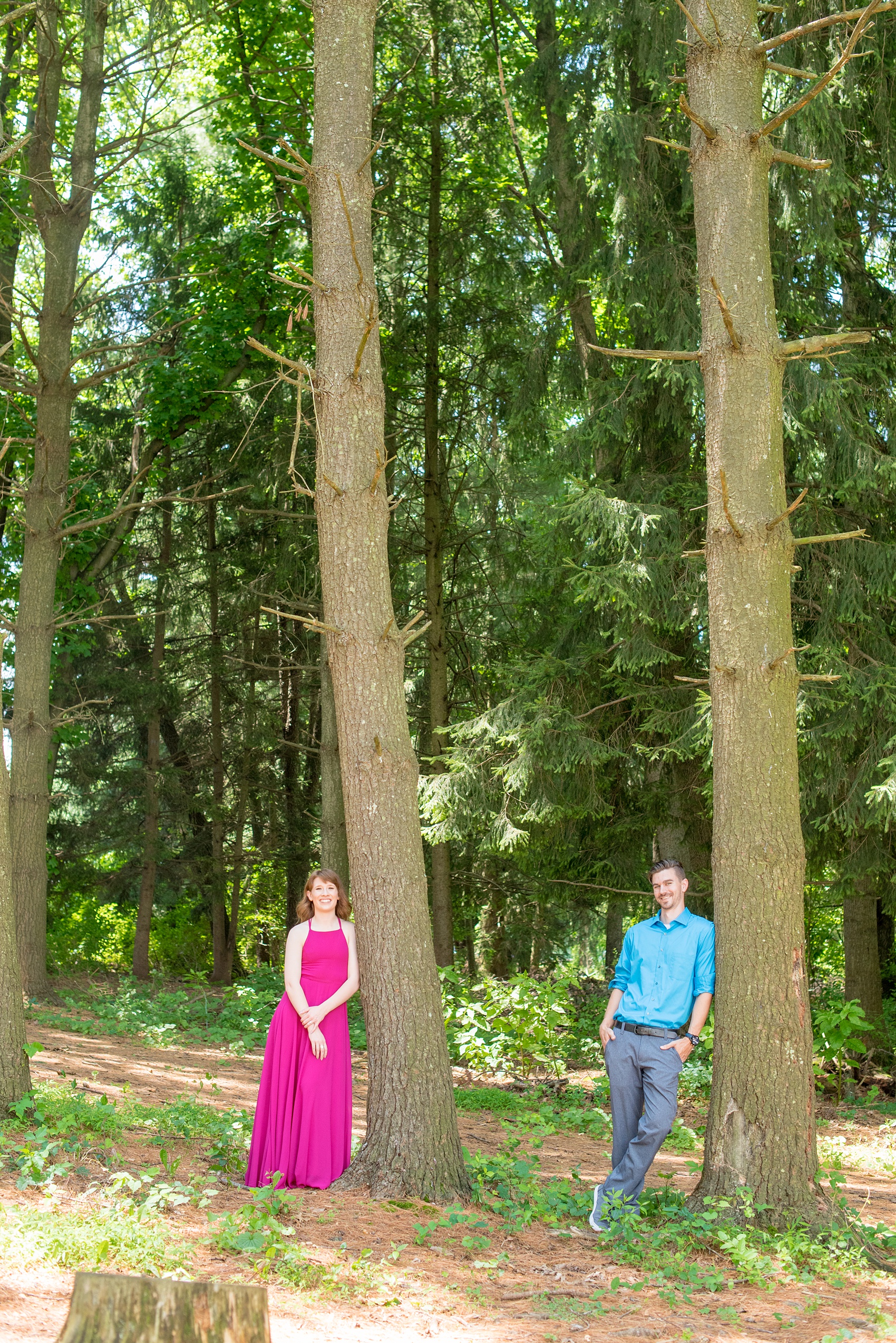 Maryland summer engagement photos by Mikkel Paige Photography. This couple wore semi-formal outfits with the bride in a beautiful, sexy back fuchsia pink gown and the groom in a blue button down and grey pants. Their elegant outdoor park pictures were perfect for the season! Click through to see more from their romantic pictures in the woods! #mikkelpaige #summerengagementphotos #marylandengagementphotos #marylandweddingphotographer #parkengagementsession #engagementphotooutfitideas #engagementphotos #savethedatephotos 