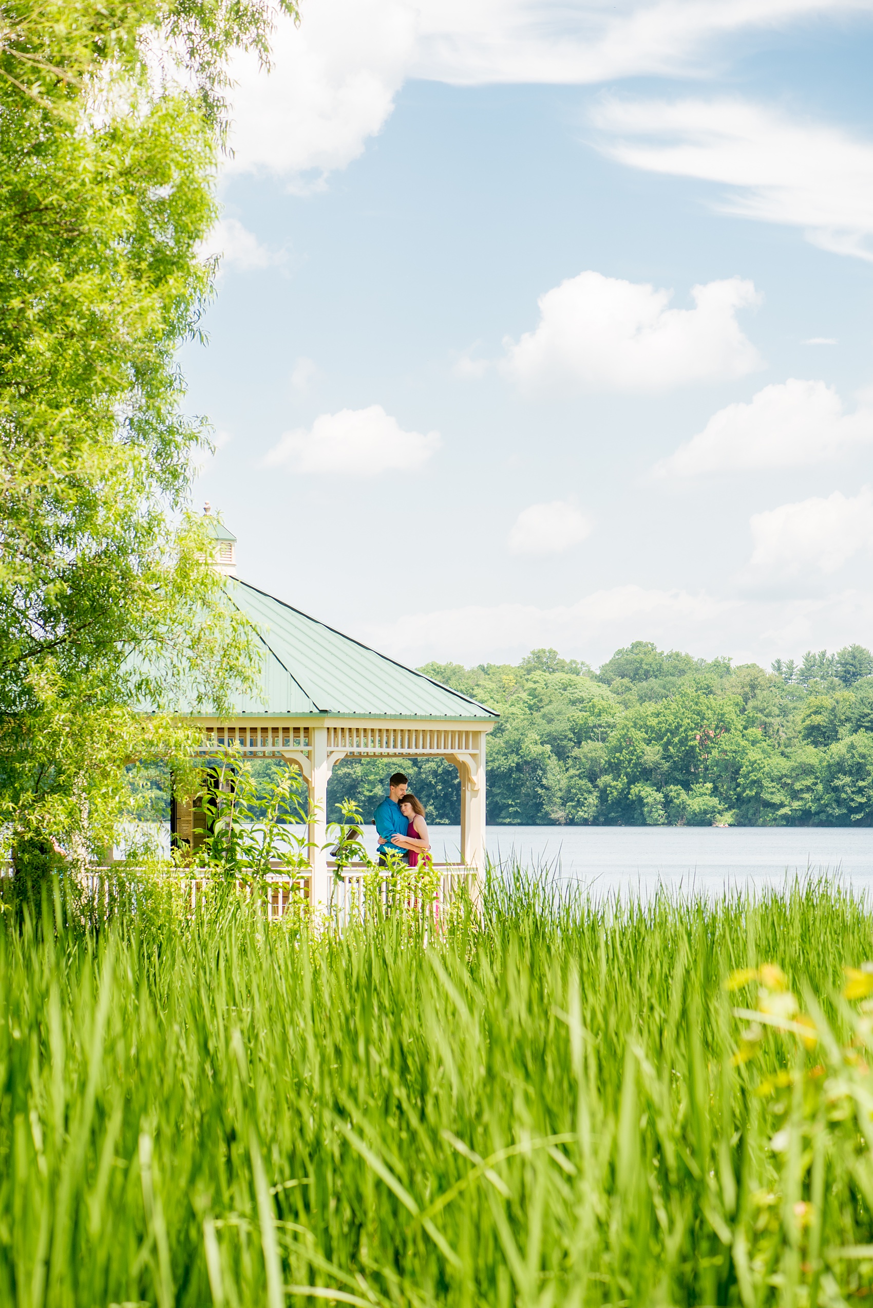 Maryland summer engagement photos by Mikkel Paige Photography. This couple wore semi-formal outfits with the bride in a beautiful, sexy back fuchsia pink gown and the groom in a blue button down and grey pants. Their elegant outdoor park pictures were perfect for the season! Click through to see more from their romantic pictures in the woods! #mikkelpaige #summerengagementphotos #marylandengagementphotos #marylandweddingphotographer #parkengagementsession #engagementphotooutfitideas #engagementphotos #savethedatephotos 