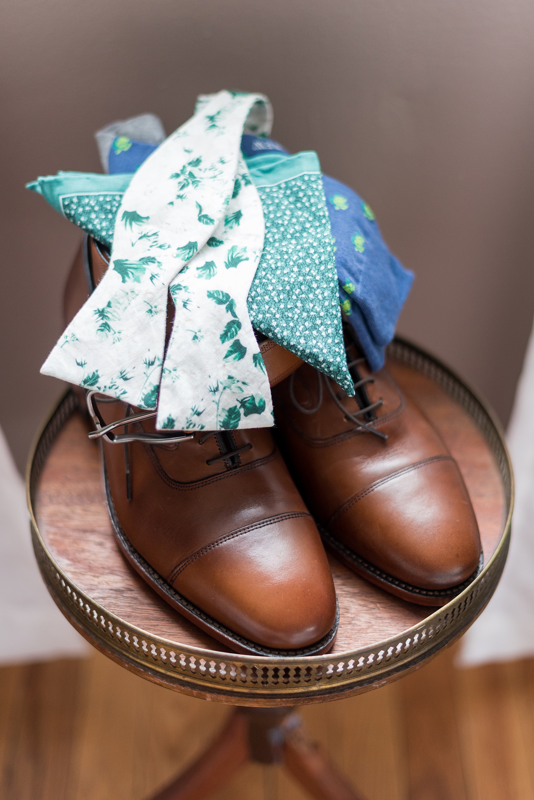 Wedding photos at Crabtree's Kittle House in Chappaqua, New York by Mikkel Paige Photography. This venue in Westchester county was the perfect place for a summer wedding where the groom wore a pattern bow tie with greenery on it, a green print pocket square, brown leather shoes and blue and green turtle socks for his alma mater, University of Maryland. Click through for more awesome information from the day like the great boutonniere! #patternbowtie #mikkelpaige #CrabtreesKittleHouse #WestchesterWeddingVenues #WestchesterWedding #summerwedding #boutonniere #bowties #creativebowtie #cutebowtie #greenpocketsquare #turtlesocks #terpsocks #goterps